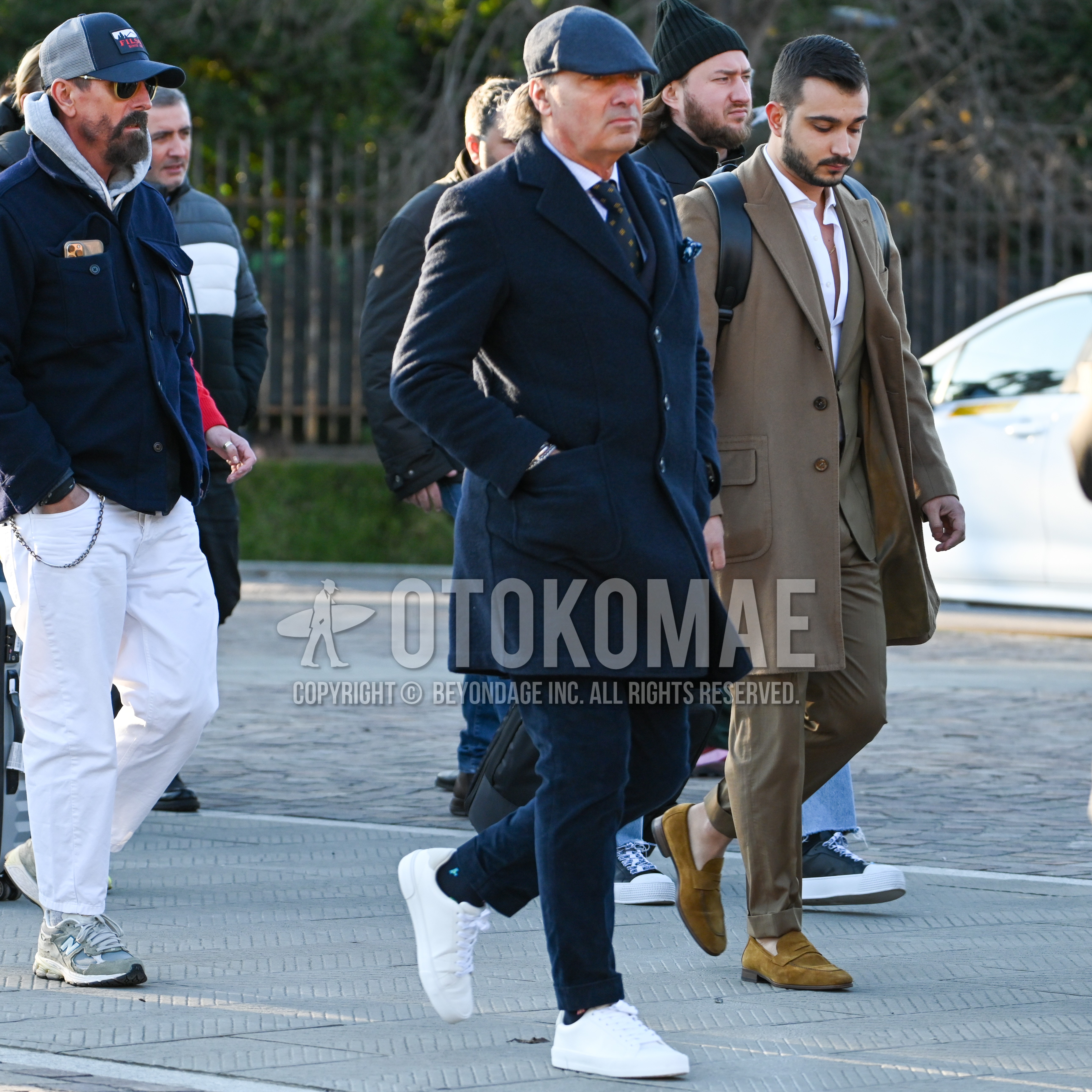 Men's autumn winter outfit with dark gray plain hunting cap, navy plain chester coat, white plain shirt, navy plain chinos, black one point socks, white low-cut sneakers, navy yellow small crest necktie.