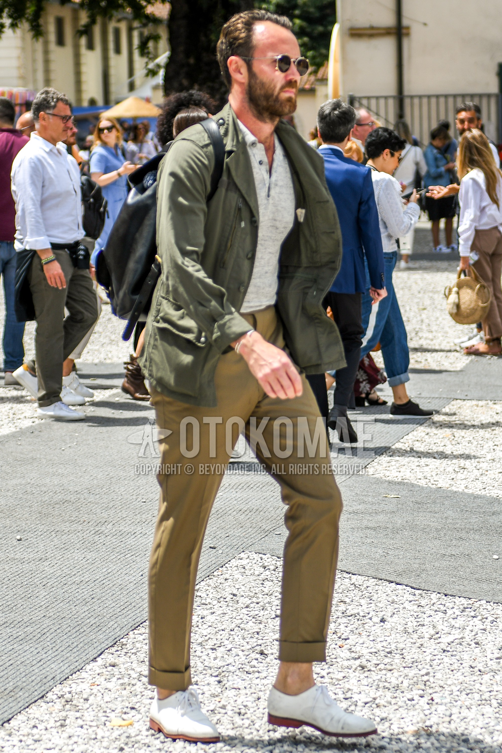 Men's spring summer autumn outfit with plain sunglasses, olive green plain tailored jacket, gray plain polo shirt, beige plain chinos, white straight-tip shoes leather shoes.