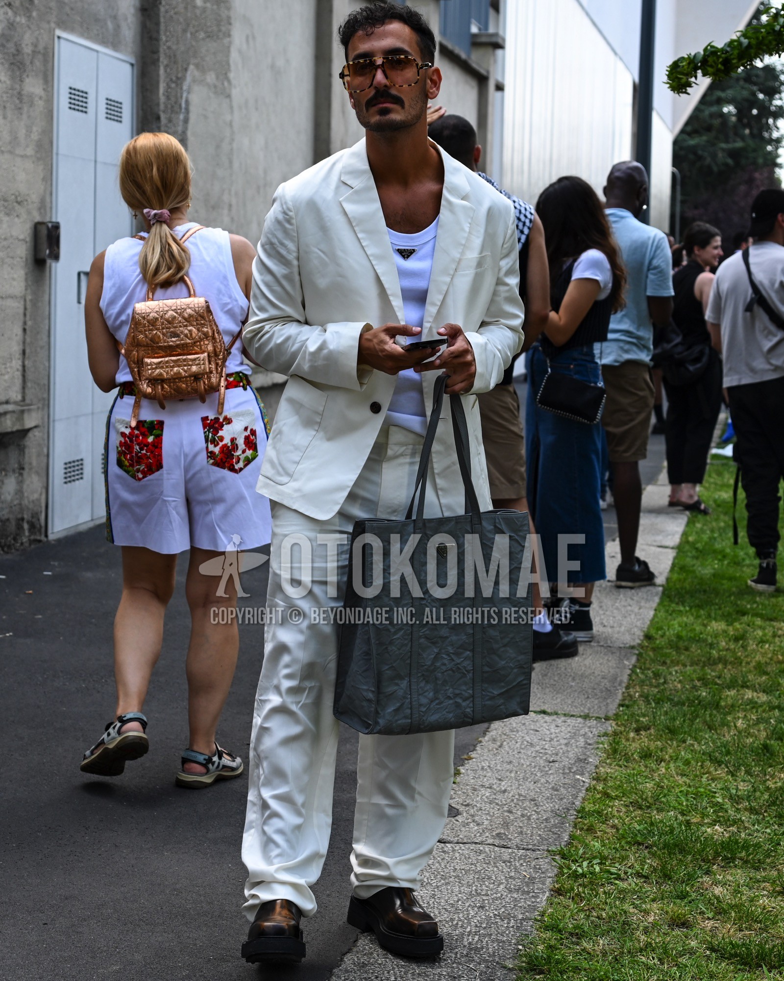 Men's spring summer autumn outfit with brown plain sunglasses, white plain tailored jacket, white plain tank top, white plain slacks, black low-cut sneakers, black plain tote bag.