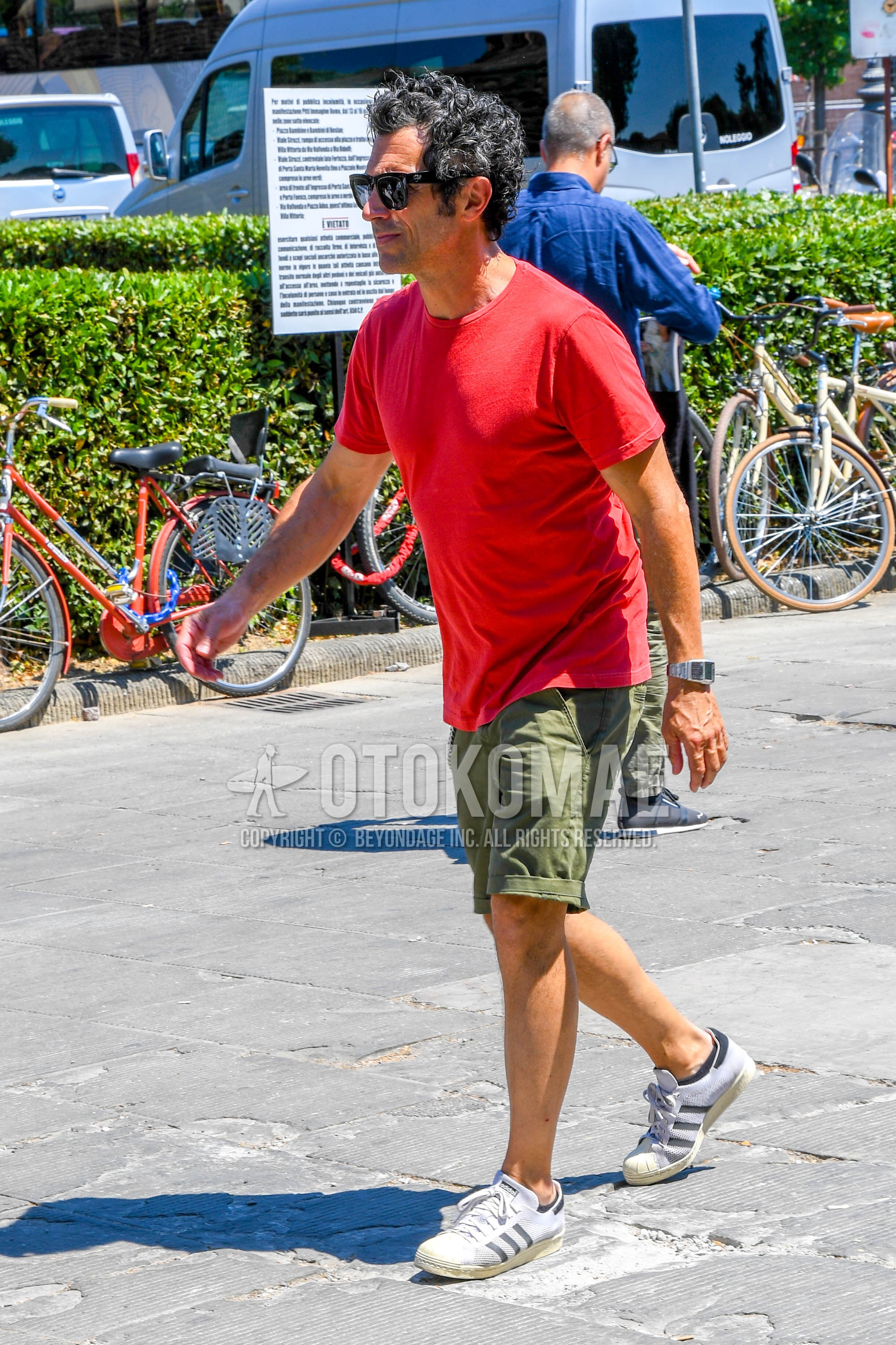 Men's summer outfit with plain sunglasses, red plain t-shirt, olive green plain short pants, white low-cut sneakers.