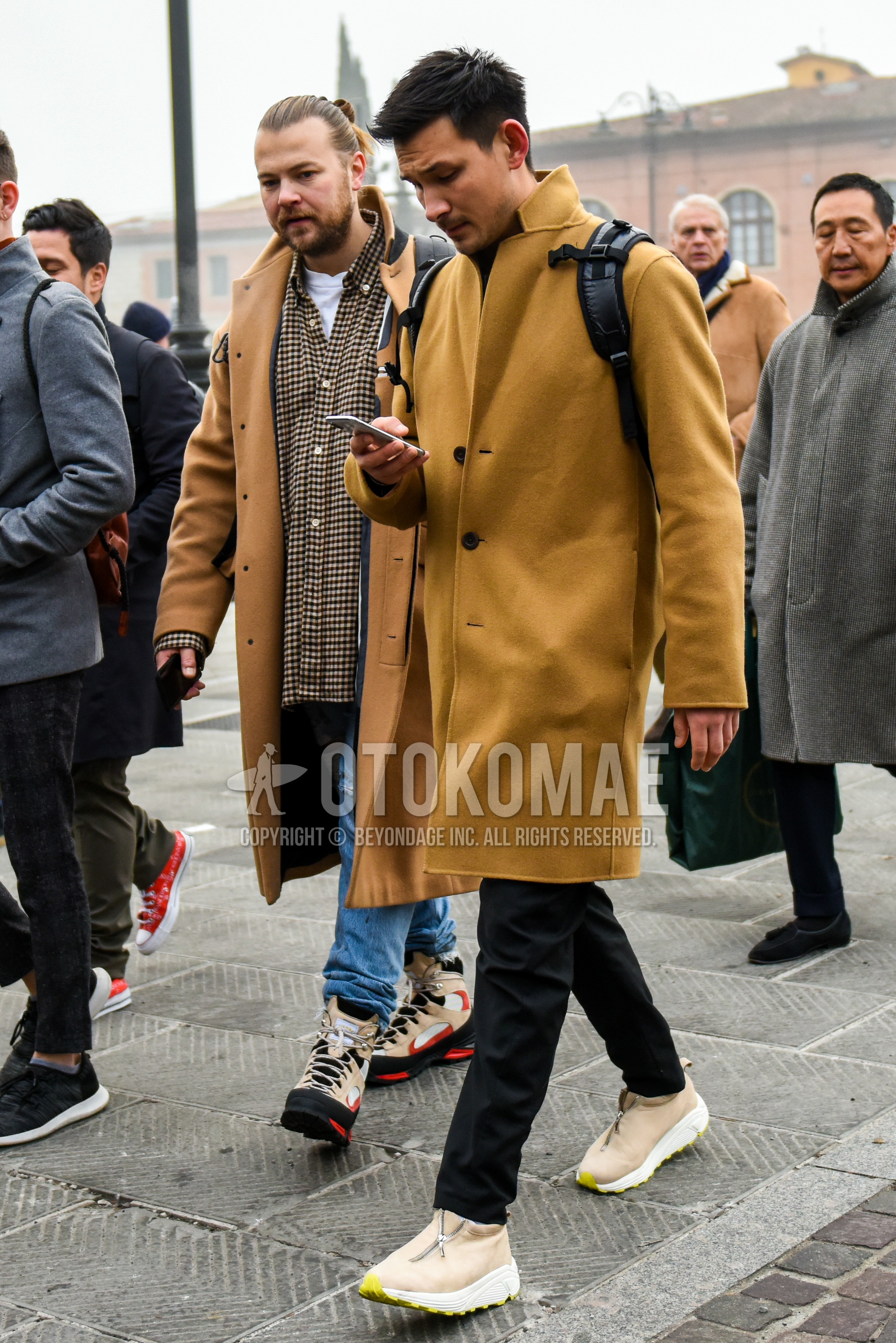 Men's winter outfit with brown plain chester coat, black plain cotton pants, beige low-cut sneakers.