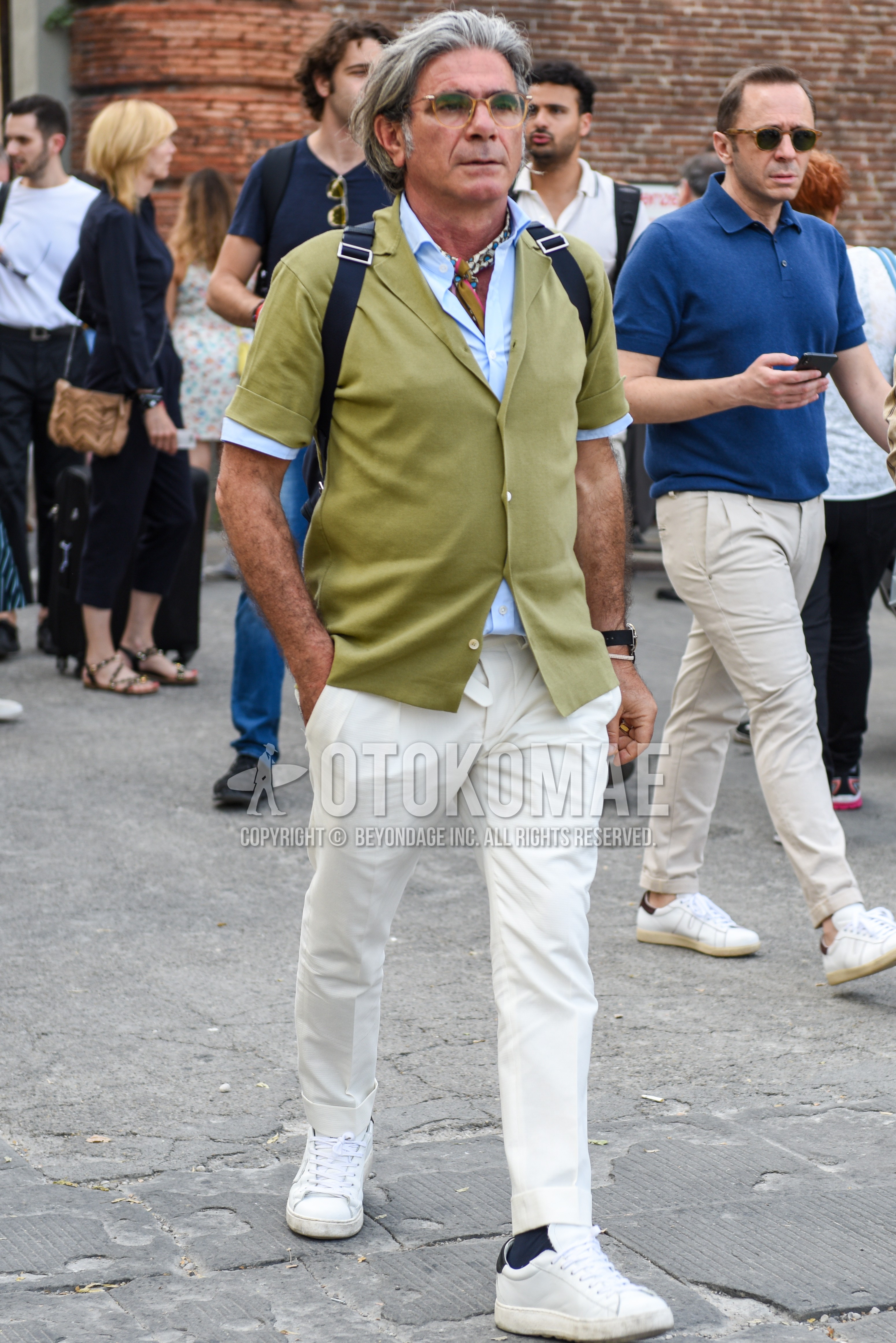 Men's summer outfit with brown plain glasses, light blue plain shirt, green plain shirt, white plain cotton pants, black plain socks, white low-cut sneakers.