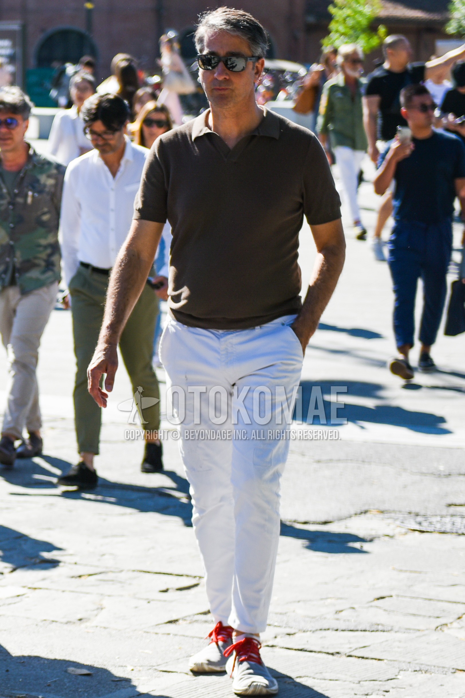 Men's spring summer outfit with black plain sunglasses, brown plain polo shirt, white plain cotton pants, white plain ankle pants, gray low-cut sneakers.