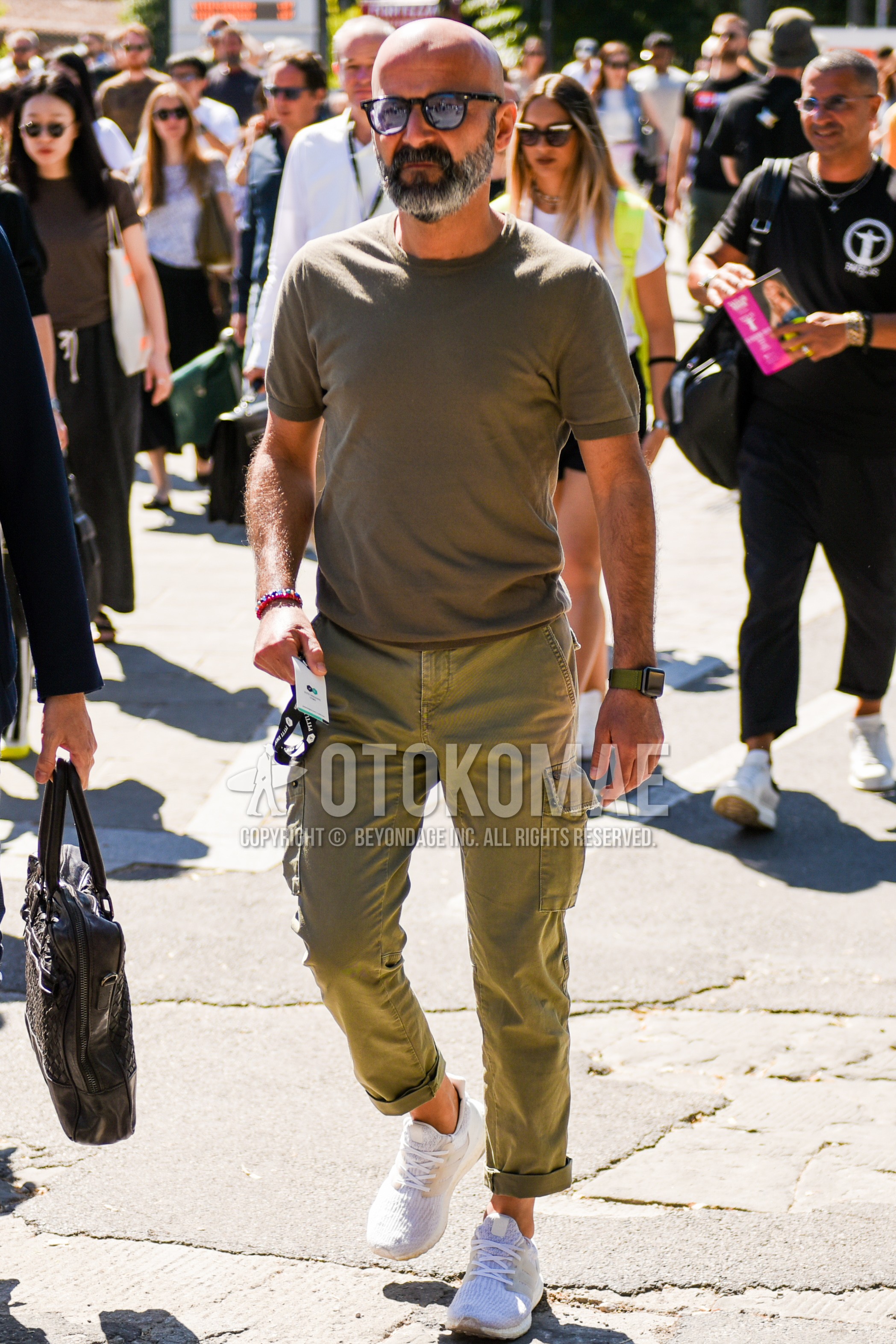 Men's summer outfit with black plain sunglasses, beige plain t-shirt, olive green plain cargo pants, white low-cut sneakers.