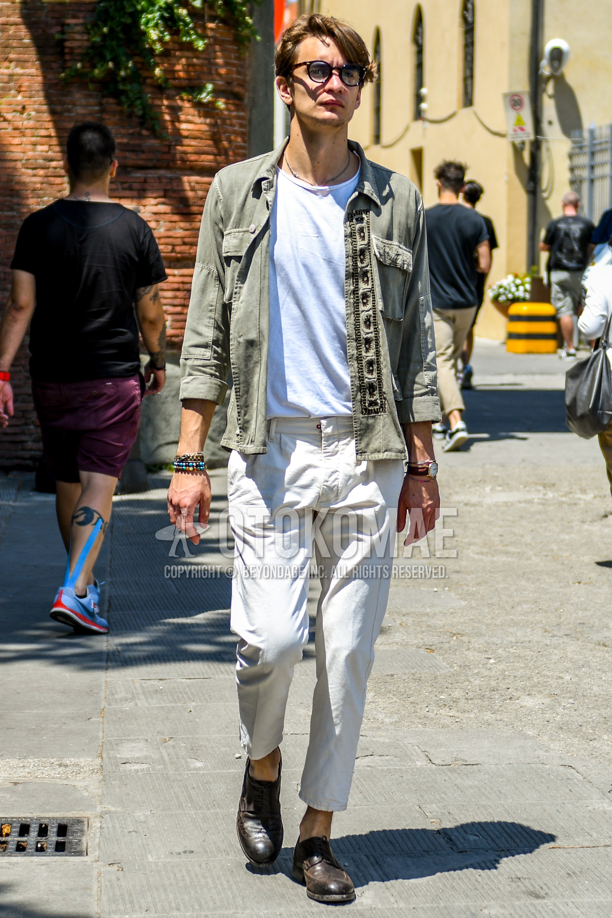 Men's spring summer outfit with plain sunglasses, green plain shirt, white plain t-shirt, white plain beltless pants, plain cropped pants, brown brogue shoes leather shoes.