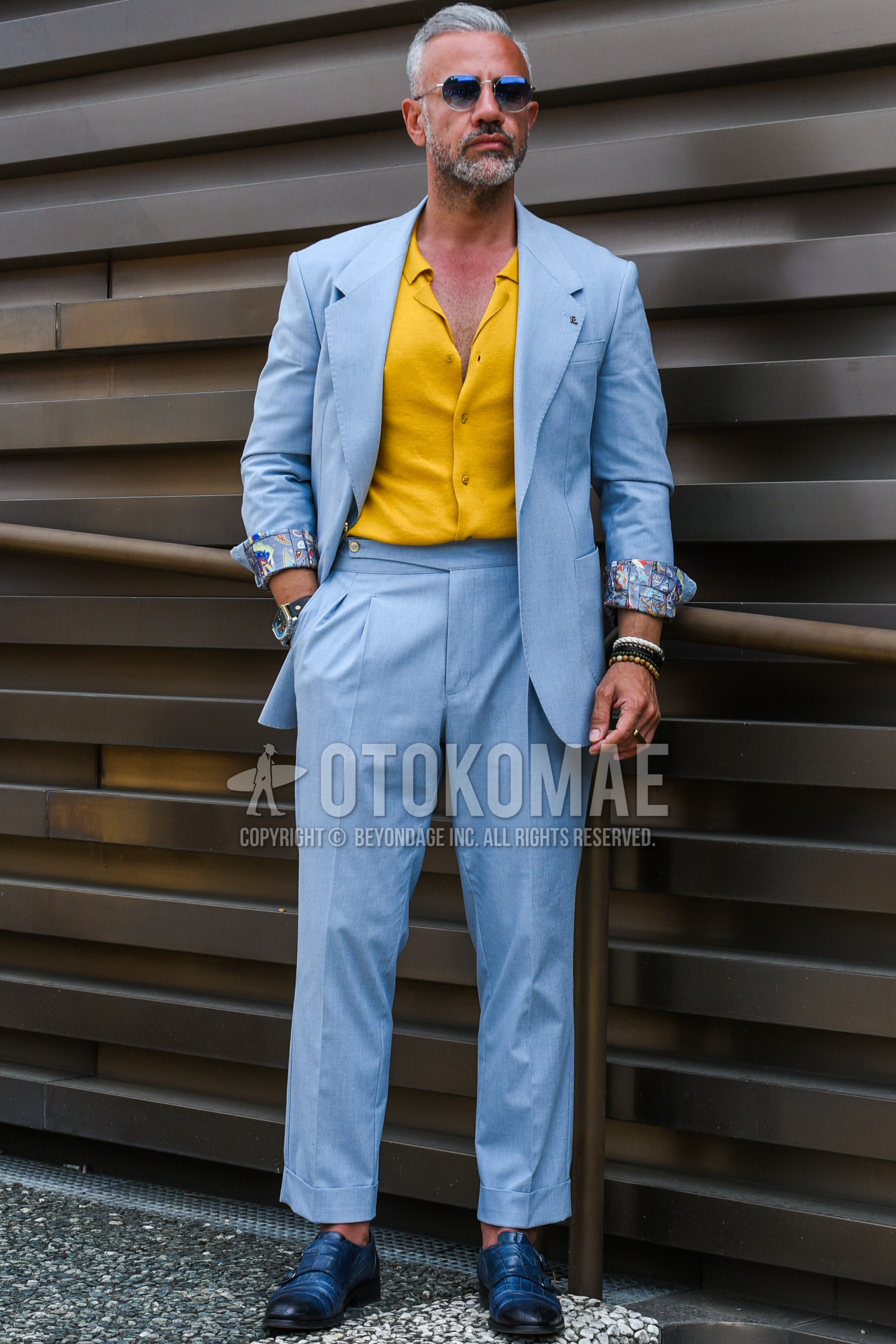 Men's spring summer autumn outfit with blue plain sunglasses, yellow plain shirt, blue navy coin loafers leather shoes, light blue plain suit.