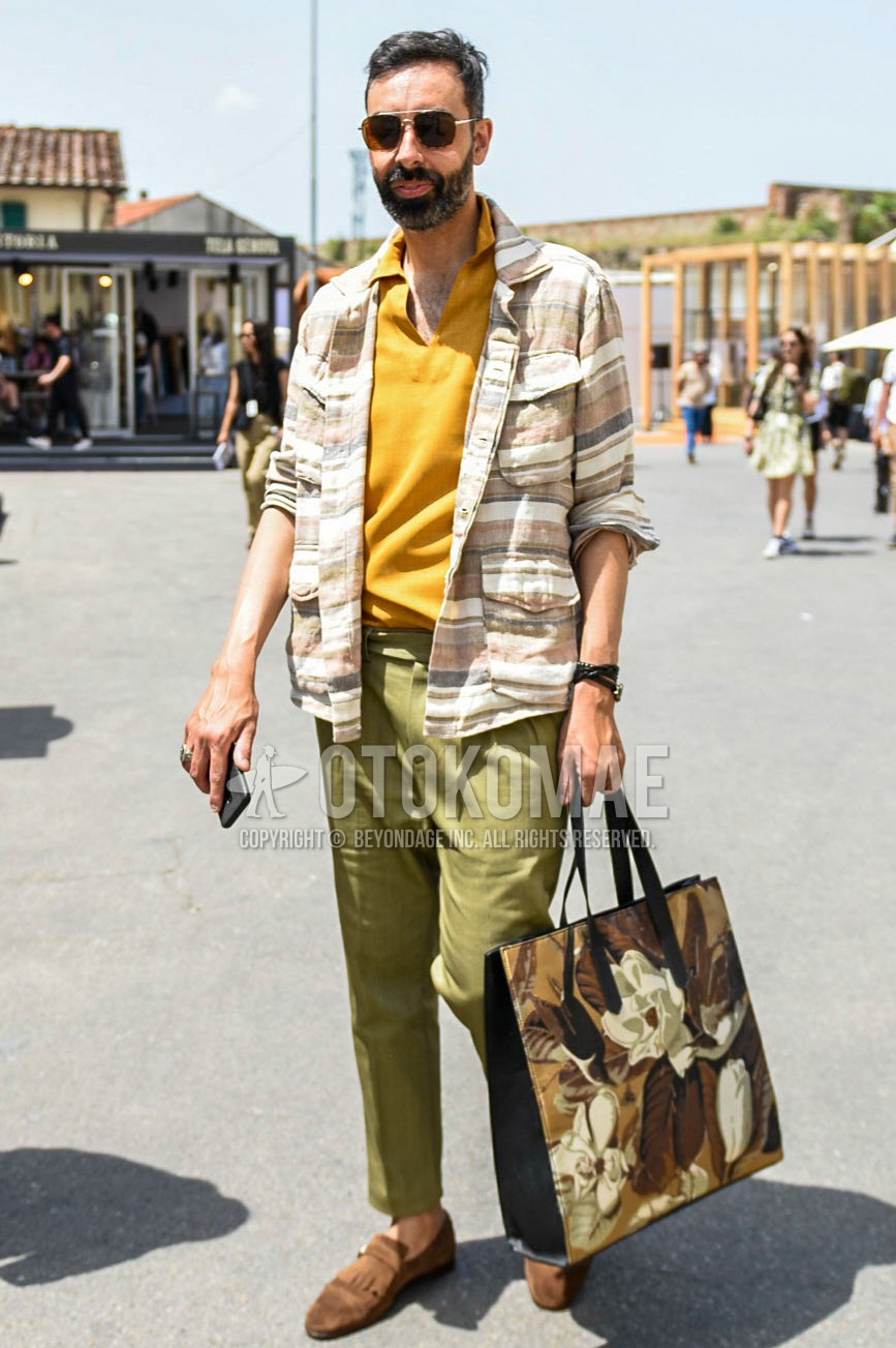Men's spring summer outfit with silver plain sunglasses, yellow plain polo shirt, beige horizontal stripes shirt, olive green plain beltless pants, olive green plain ankle pants, olive green plain pleated pants, plain chinos, brown  loafers leather shoes, multi-color bag tote bag.