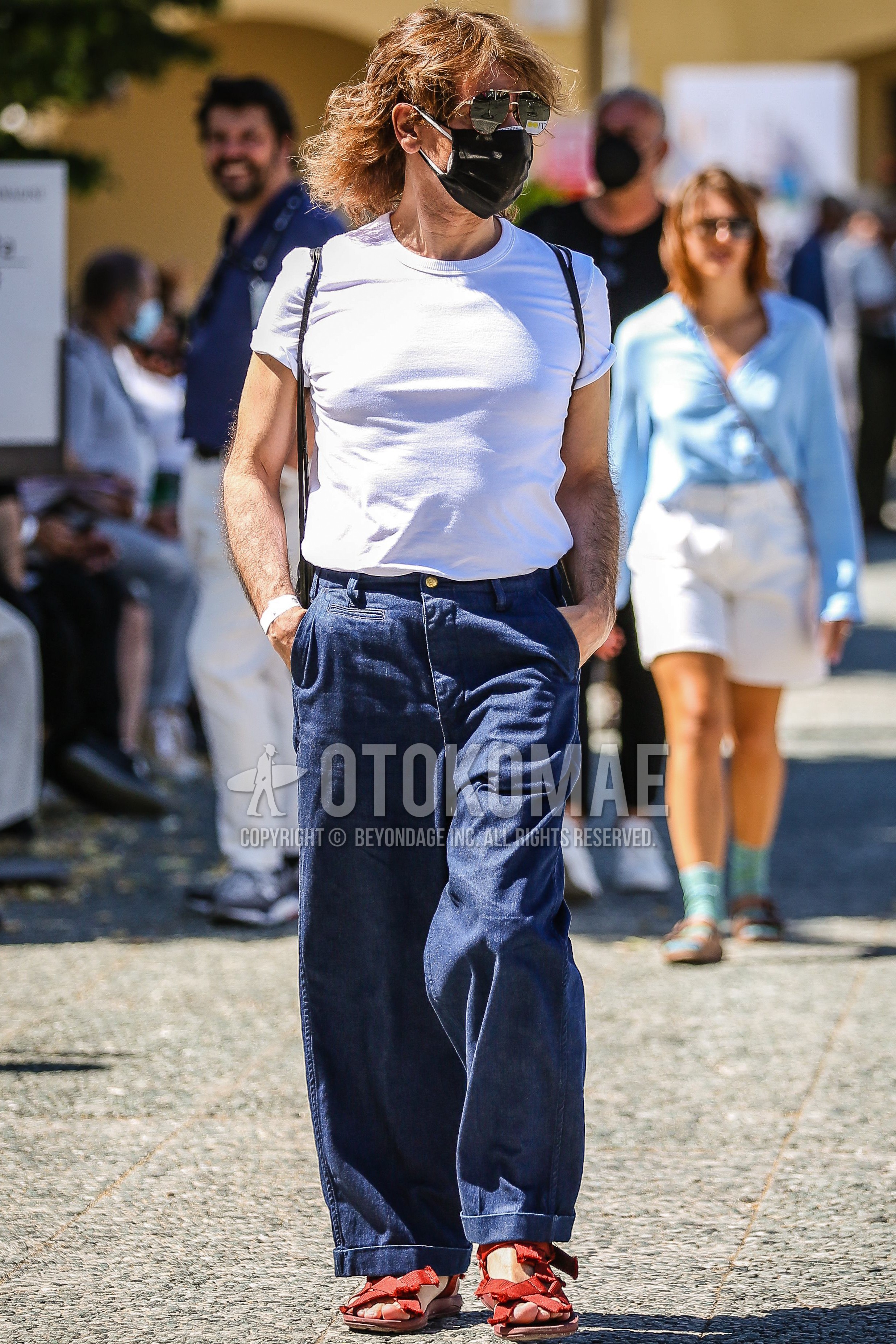 Men's spring summer outfit with silver plain sunglasses, white plain t-shirt, blue navy plain wide pants, red sport sandals.