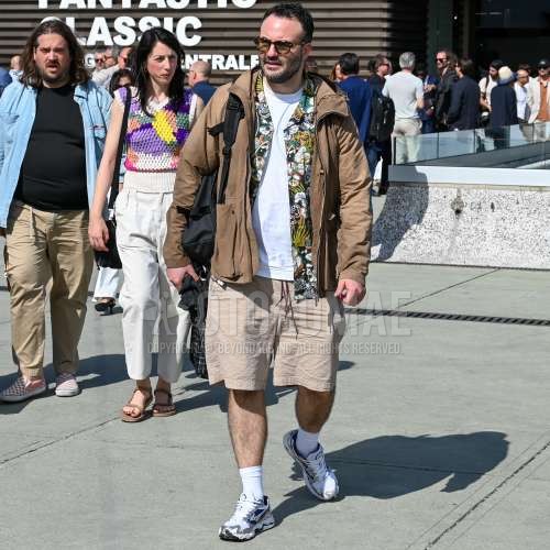 黒べっ甲のサングラス、ベージュ無地のアウター、開襟　オープンカラーのマルチカラー無地のシャツ、白無地のTシャツ、ベージュ無地のショートパンツ、白無地のソックス、白ローカットのスニーカー、黒無地のバックパックを合わせた春夏のメンズコーデ・着こなし。