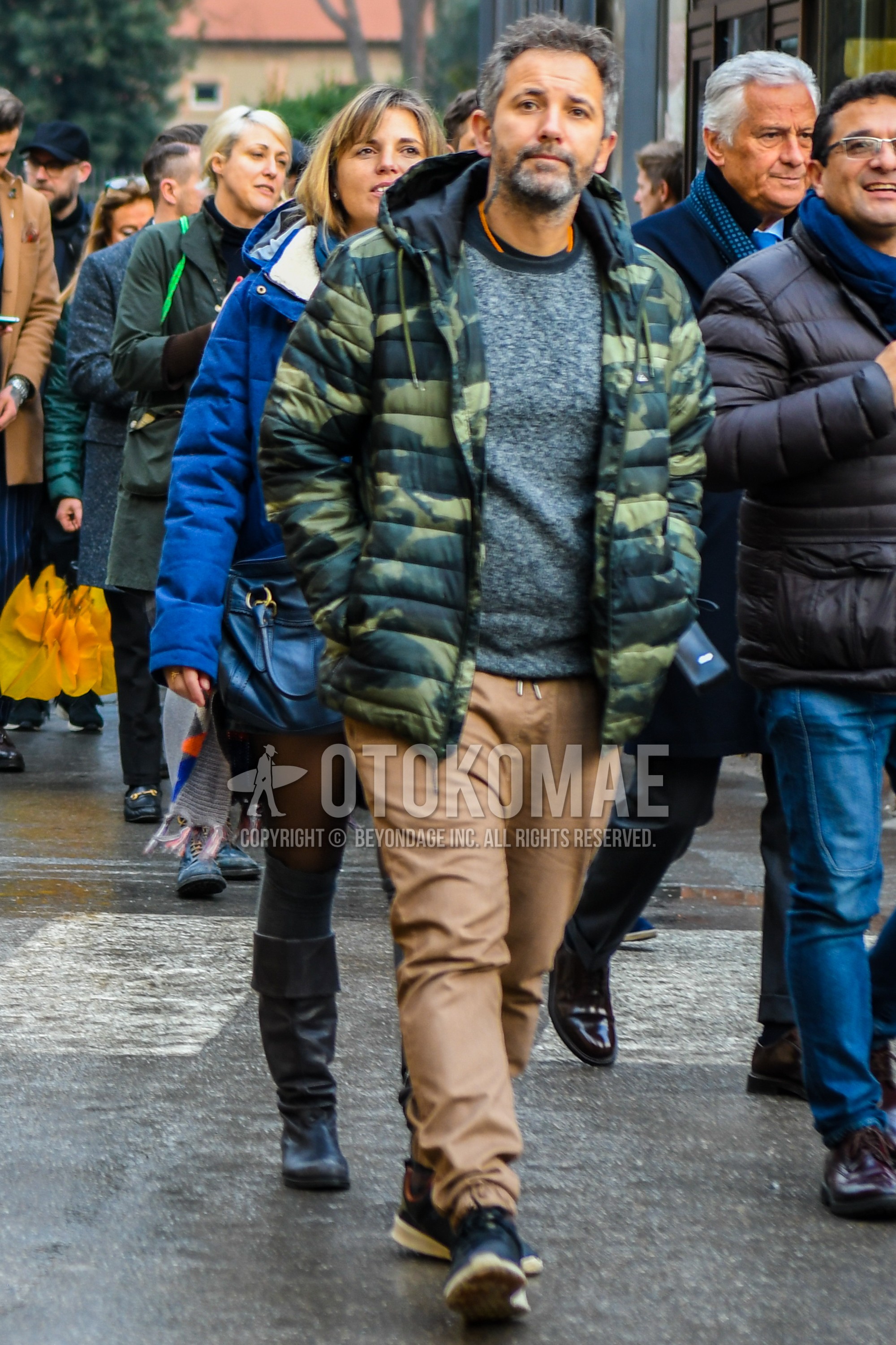 Men's winter outfit with green camouflage down jacket, gray plain sweater, brown plain easy pants, navy low-cut sneakers.