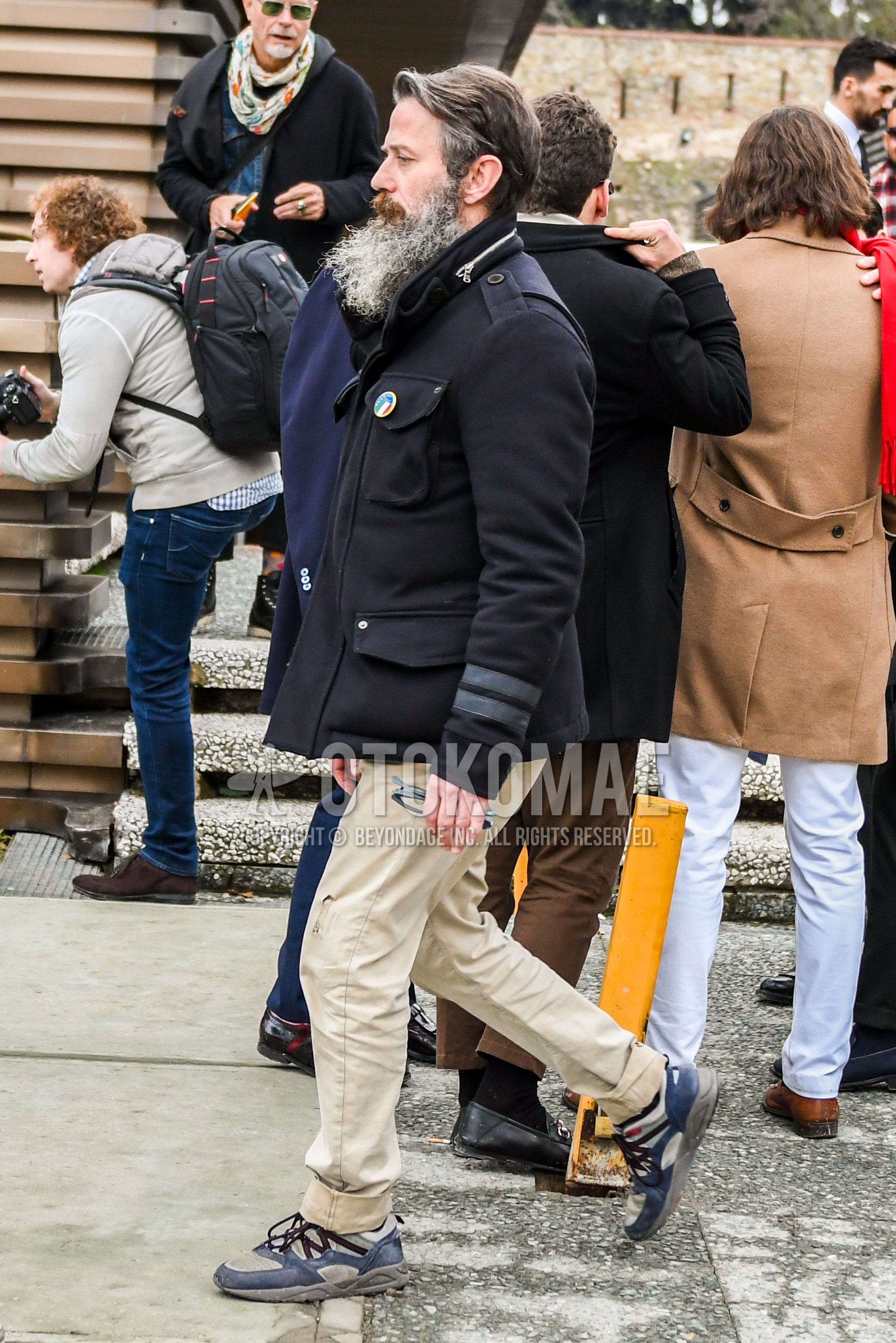 Men's winter outfit with black plain M-65, beige plain chinos, navy beige low-cut sneakers.