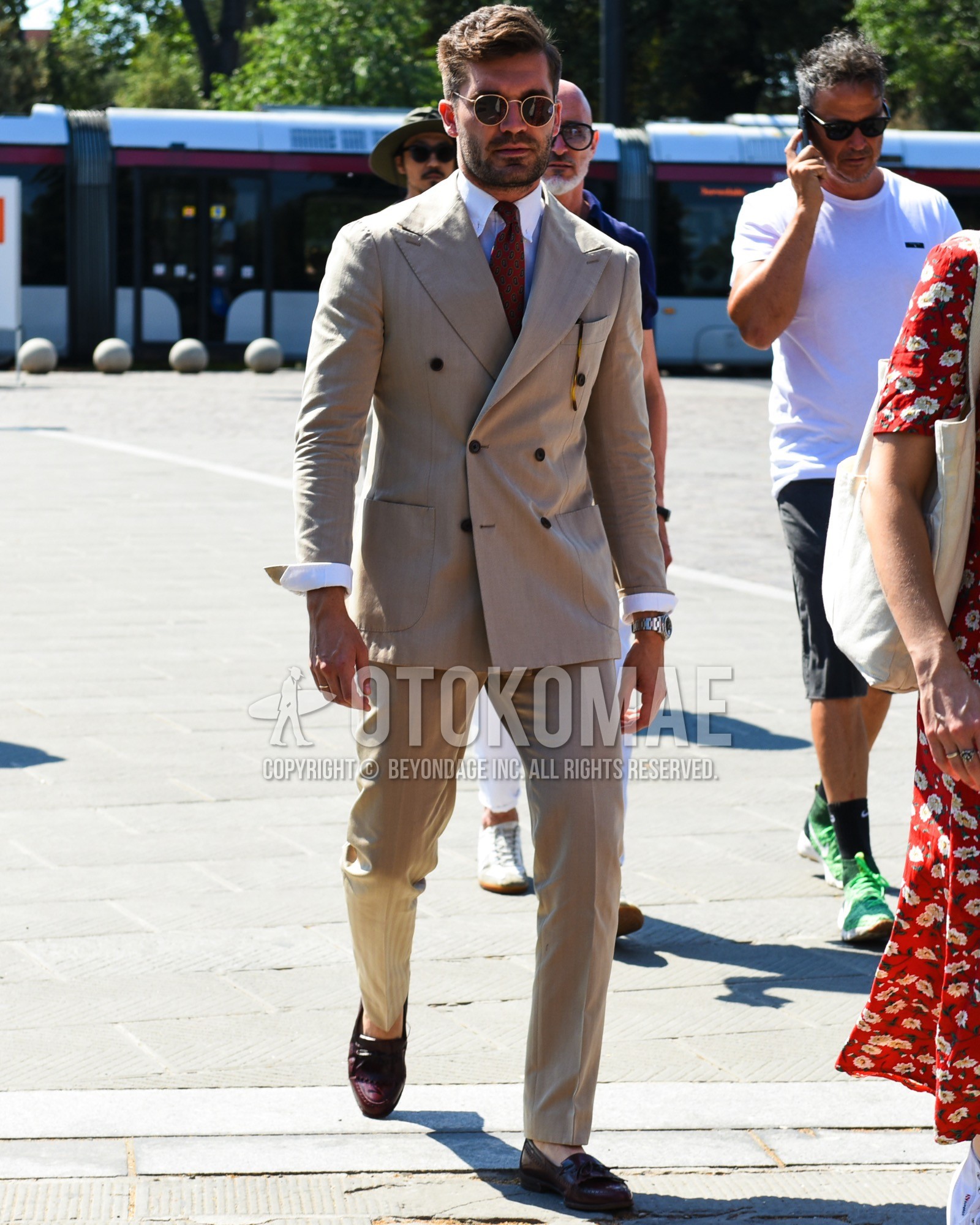 Men's spring summer outfit with gold plain sunglasses, white plain shirt, red tassel loafers leather shoes, beige stripes suit, red small crest necktie.