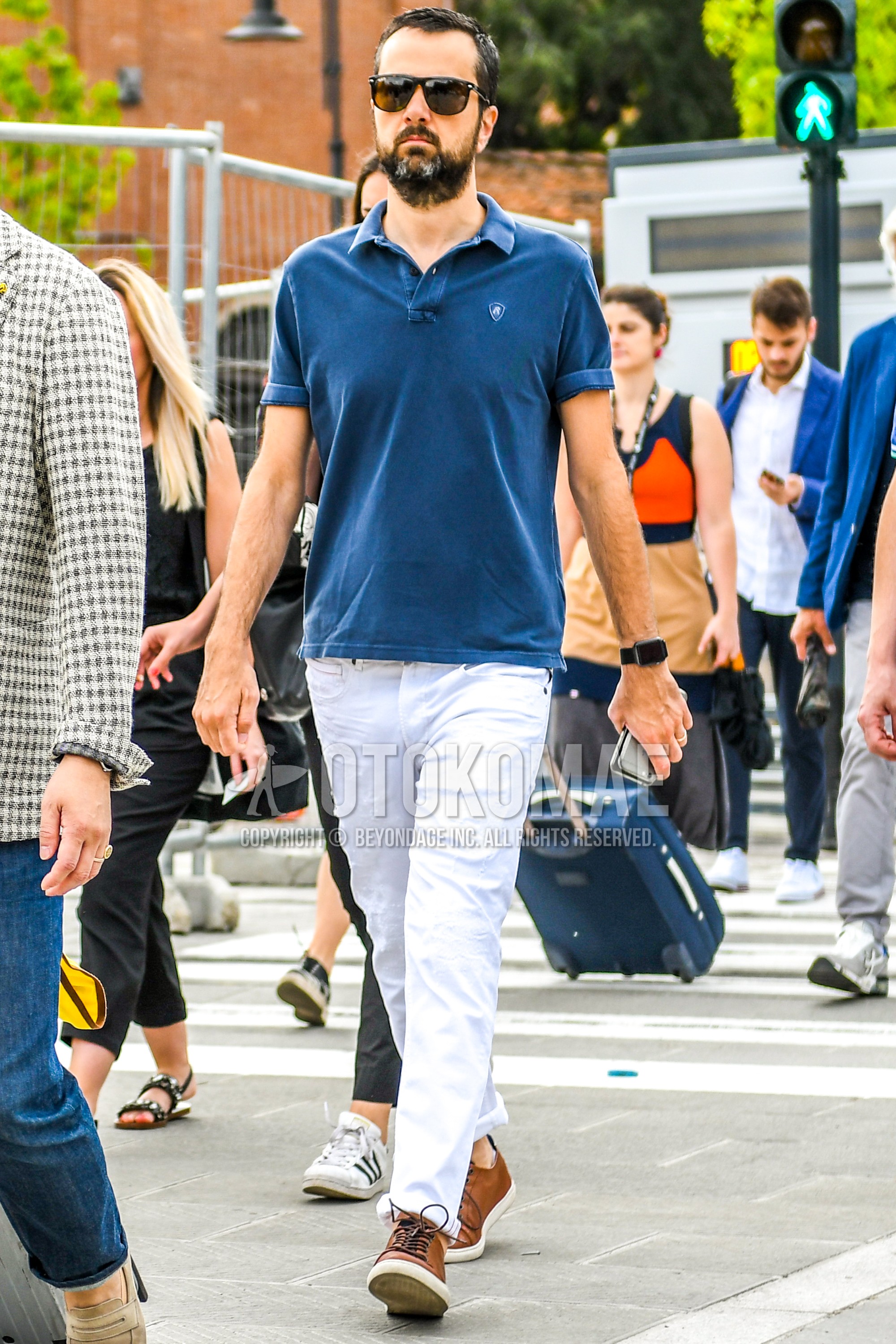 Men's spring summer outfit with black plain sunglasses, blue plain polo shirt, white plain damaged jeans, brown low-cut sneakers.