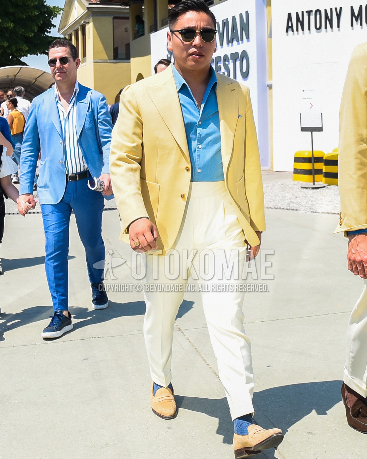 Men's spring summer autumn outfit with black plain sunglasses, yellow plain tailored jacket, blue plain shirt, white plain slacks, white plain pleated pants, navy plain socks, beige coin loafers leather shoes.