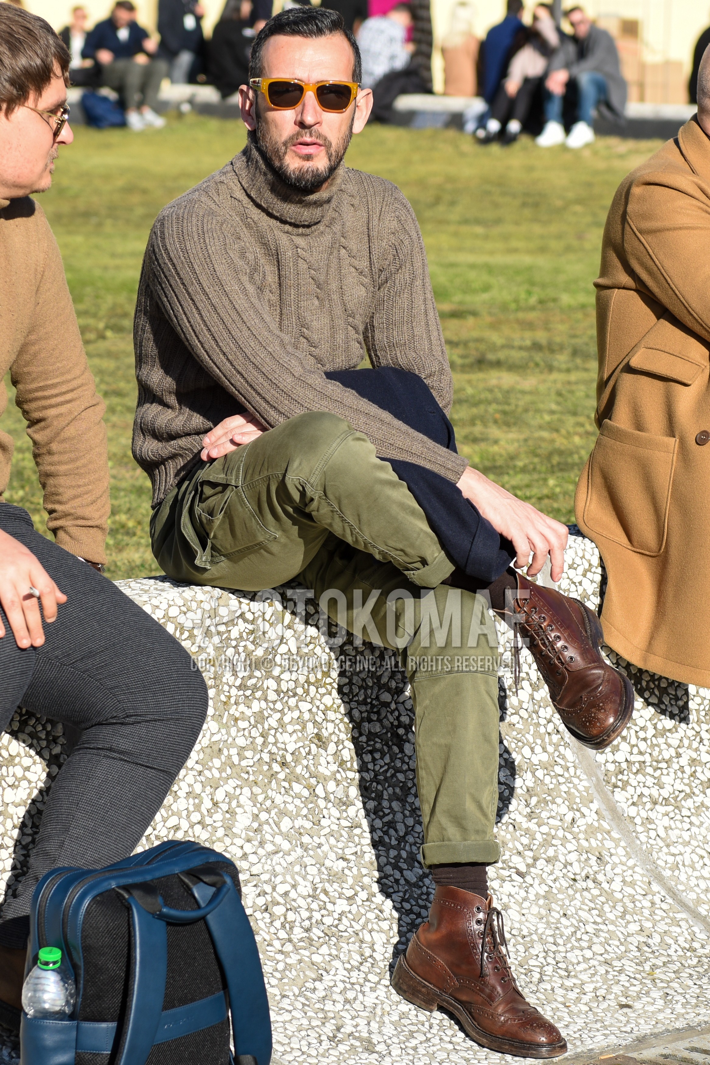 Men's spring autumn outfit with beige plain sunglasses, gray plain turtleneck knit, olive green plain chinos, brown plain socks, brown  boots.