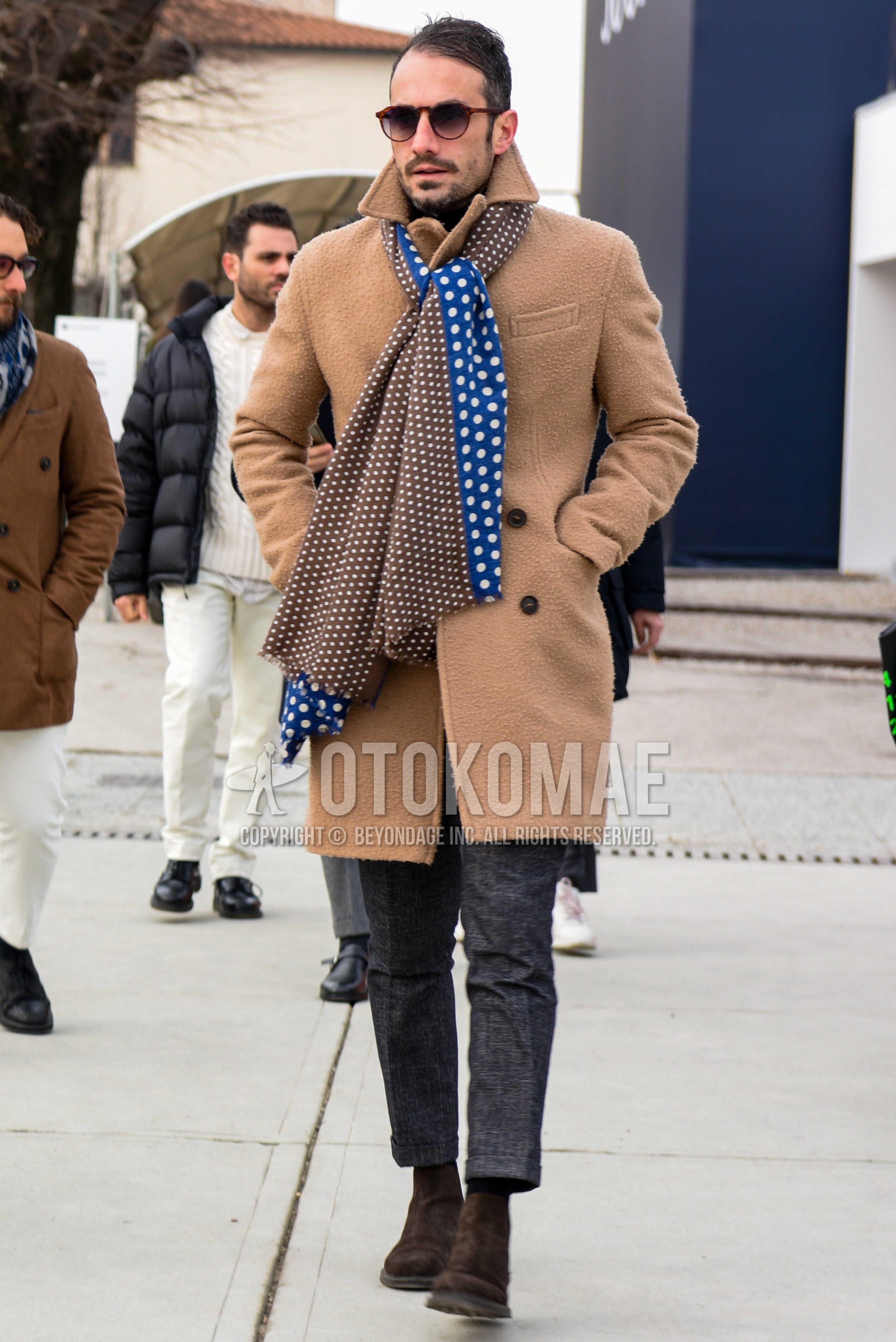 Men's autumn winter outfit with brown tortoiseshell sunglasses, brown blue dots scarf, beige plain chester coat, gray check slacks, gray check cropped pants, brown side-gore boots.