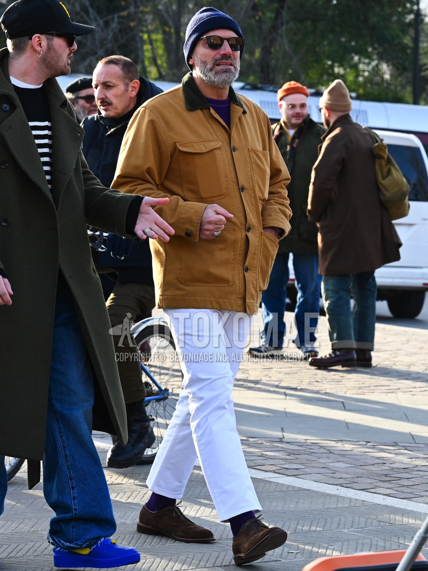 Men's autumn winter outfit with navy plain knit cap, black plain sunglasses, beige plain coverall, purple plain sweatshirt, white plain cotton pants, purple plain socks, brown brogue shoes leather shoes.