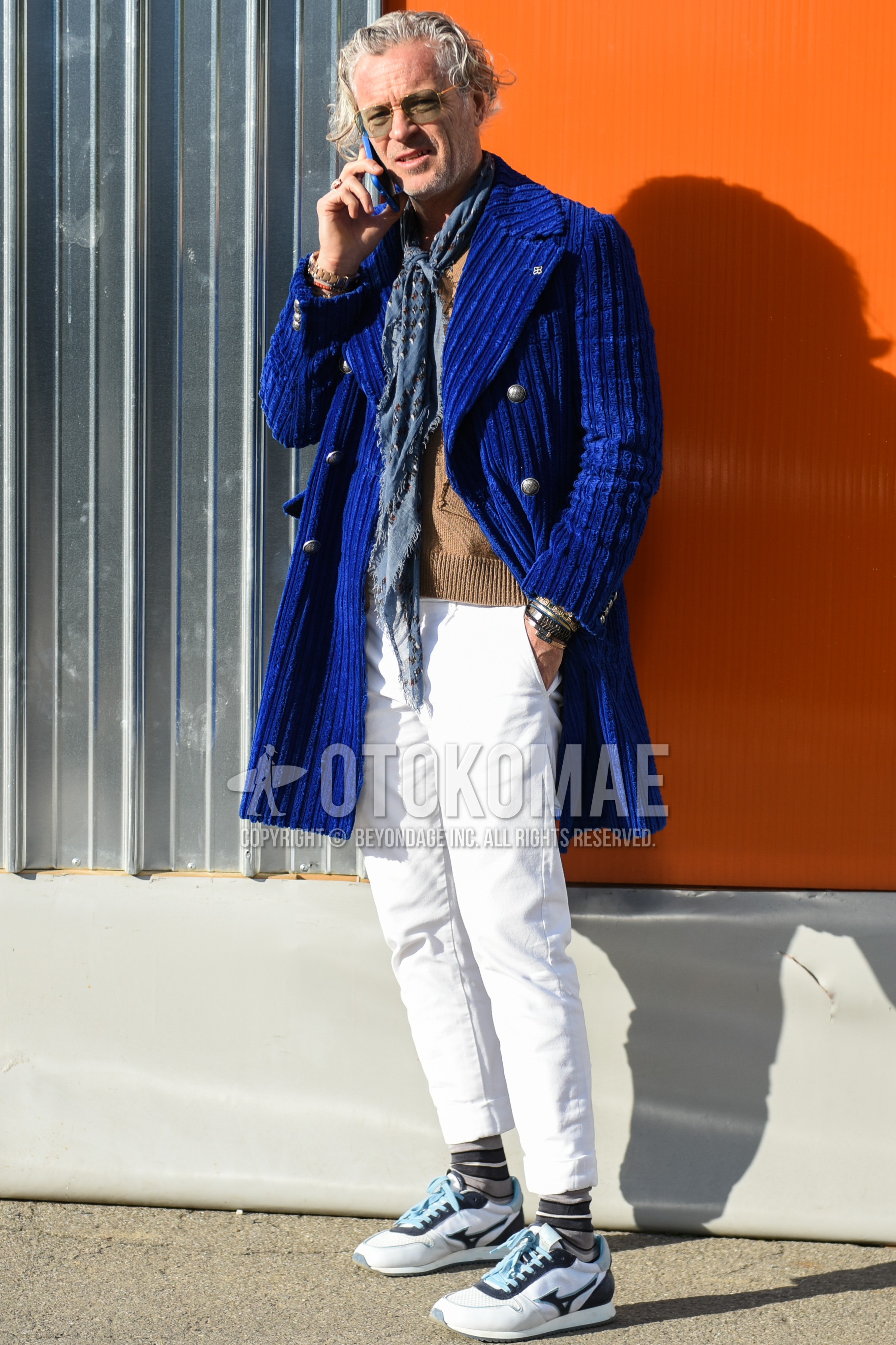 Men's autumn winter outfit with gold plain sunglasses, gray scarf scarf, blue plain ulster coat, beige plain sweater, white plain cotton pants, gray horizontal stripes socks, white low-cut sneakers.
