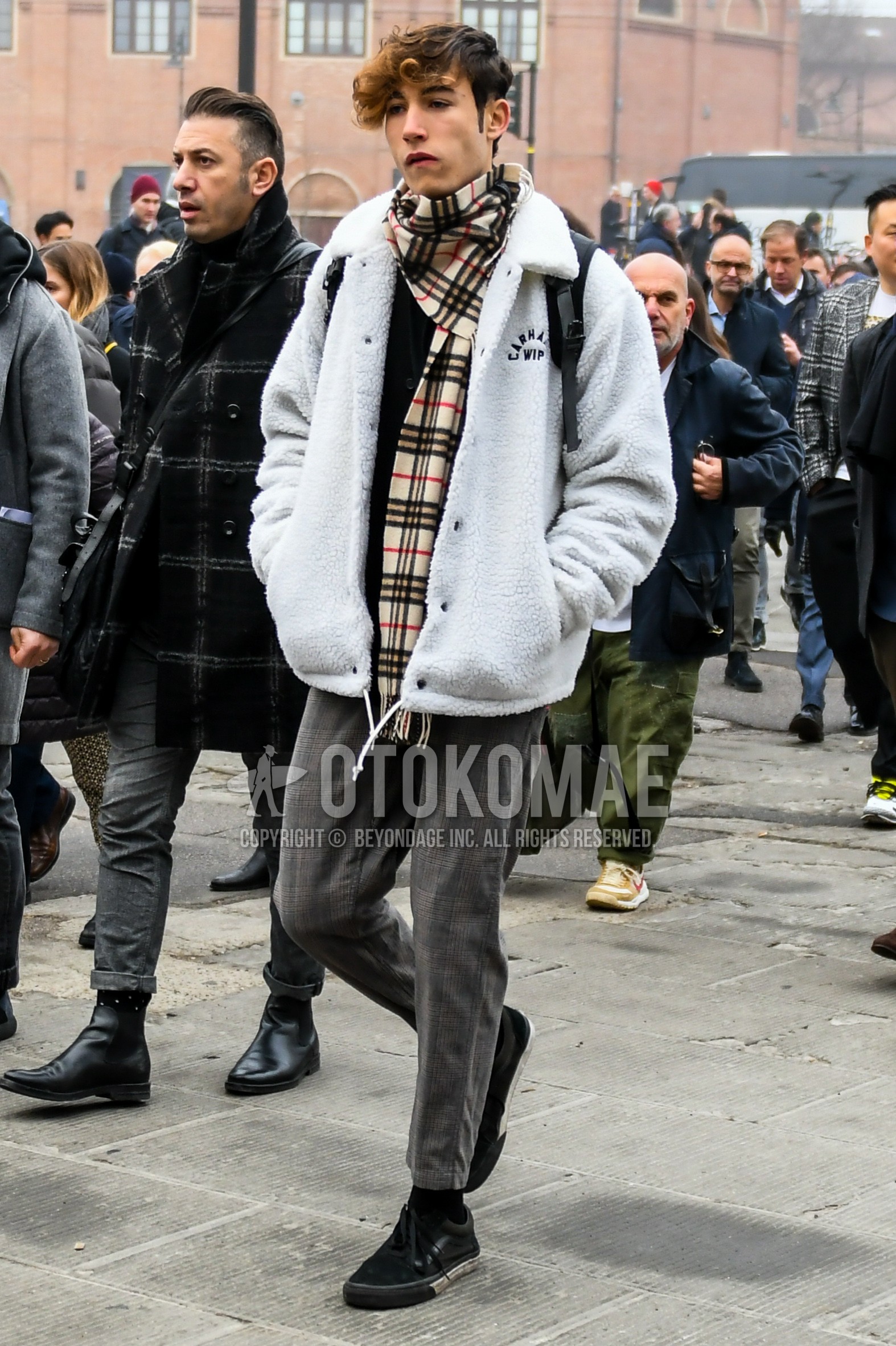 Men's autumn winter outfit with beige check scarf, white plain coach jacket, gray check slacks, black plain socks, black low-cut sneakers.