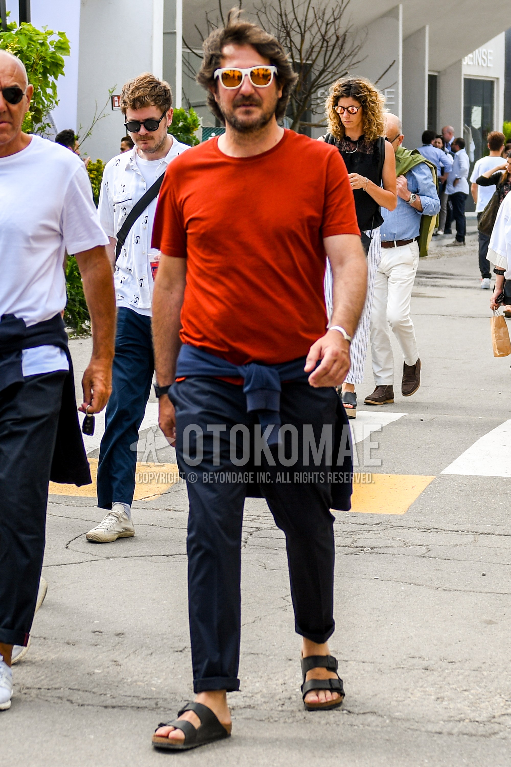 Men's summer outfit with plain sunglasses, red plain t-shirt, navy plain cotton pants, black leather sandals.
