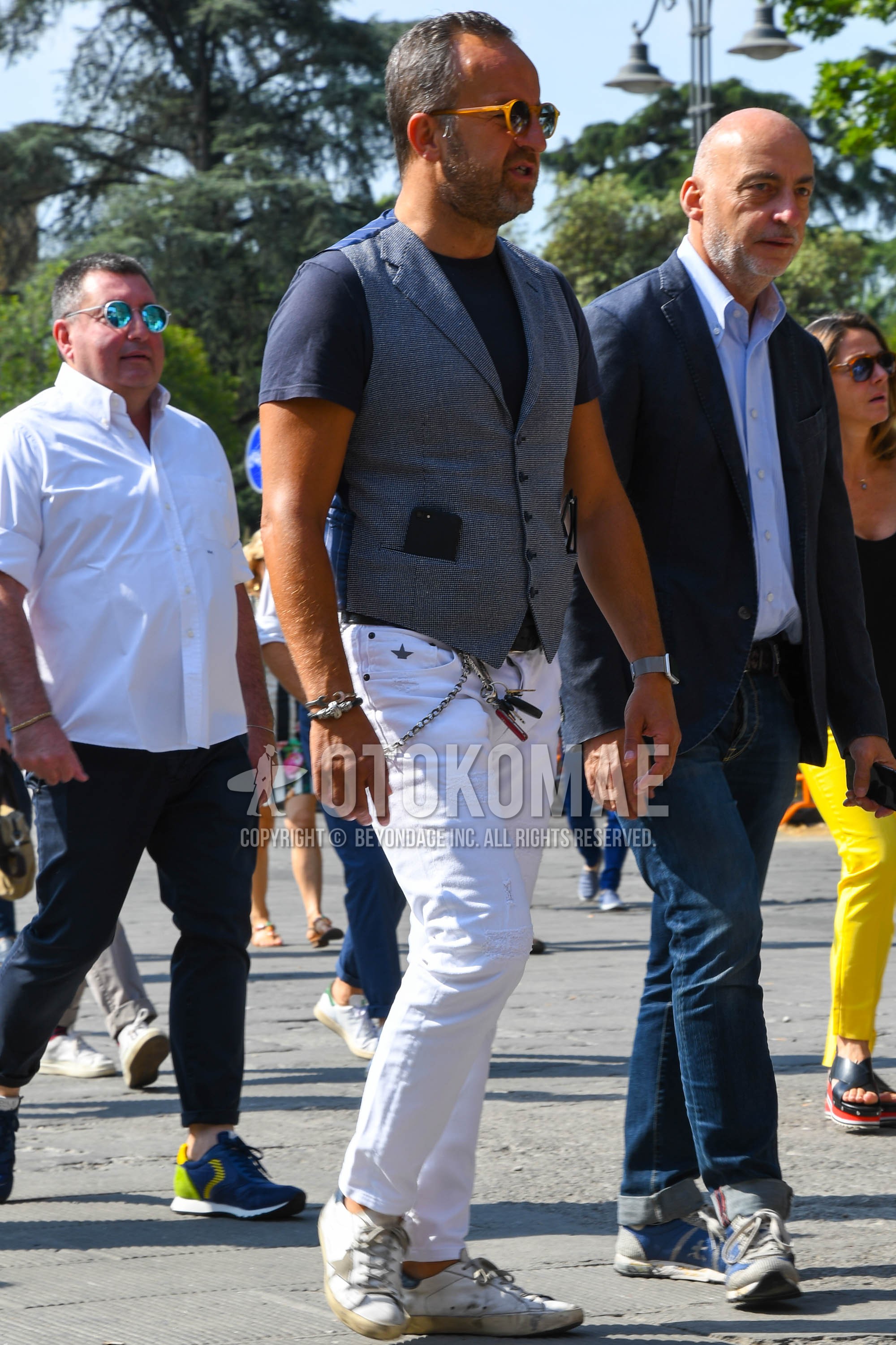 Men's summer outfit with plain sunglasses, gray check gilet, navy plain t-shirt, white plain damaged jeans, white low-cut sneakers.