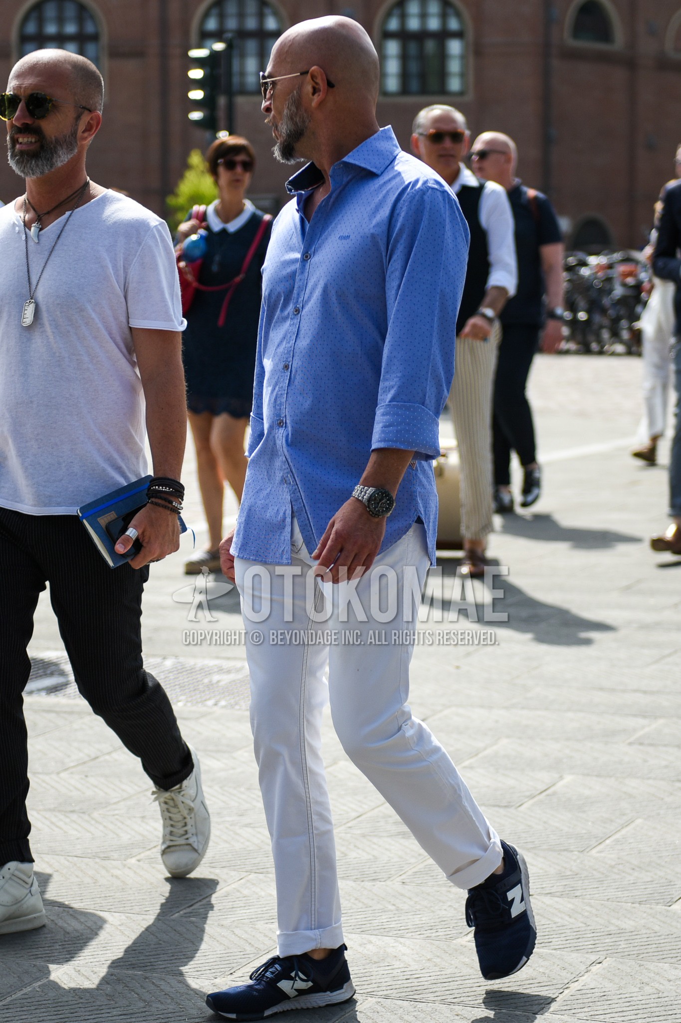 Men's spring summer outfit with plain sunglasses, light blue dots shirt, white plain cotton pants, navy low-cut sneakers.
