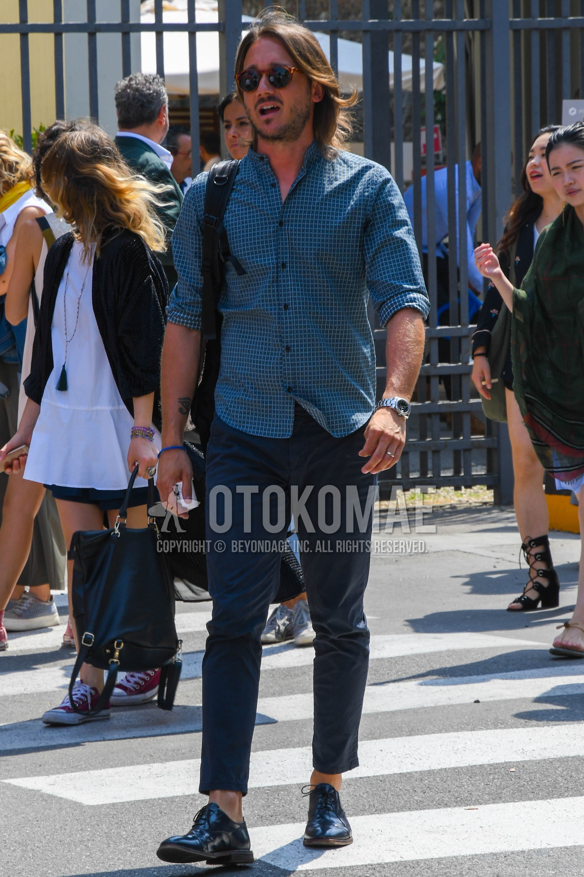 Men's spring summer outfit with brown tortoiseshell sunglasses, blue check shirt, navy plain chinos, navy plain ankle pants, black straight-tip shoes leather shoes.