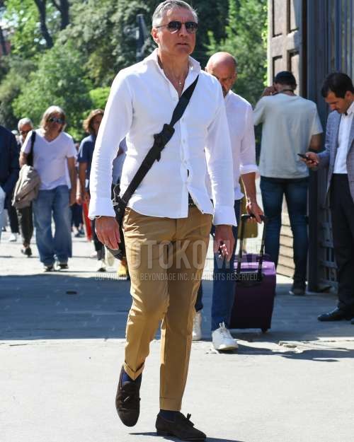 黒無地のサングラス、白無地のシャツ、ブラウン無地のレザーベルト、ブルー無地のスラックス、ネイビー無地のソックス、ブラウンタッセルローファーの革靴、ブラウンスエードシューズの革靴、黒無地のショルダーバッグを合わせた夏春のメンズコーデ・着こなし。