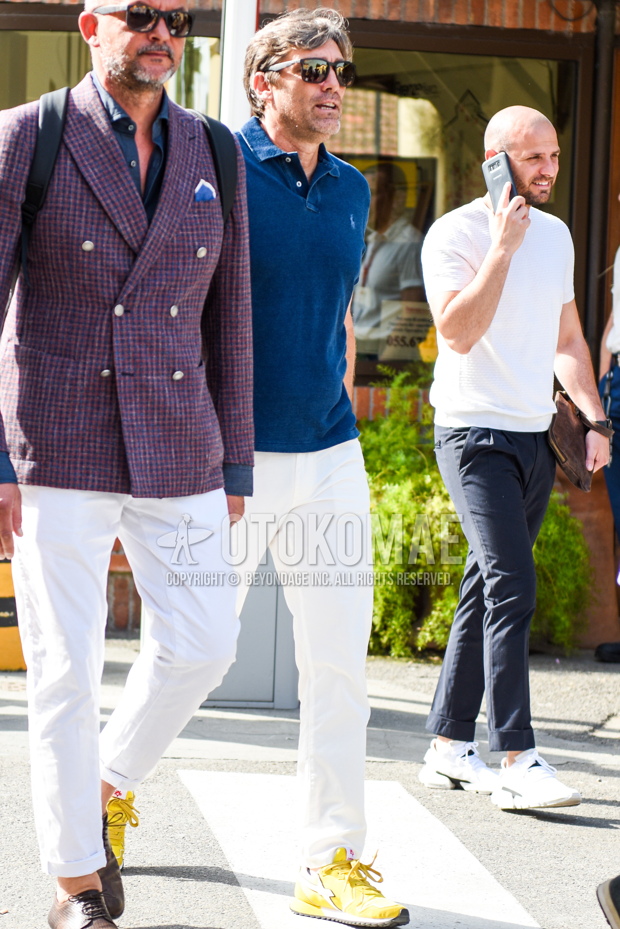 Men's spring summer outfit with black plain sunglasses, blue plain polo shirt, white plain cotton pants, yellow low-cut sneakers.