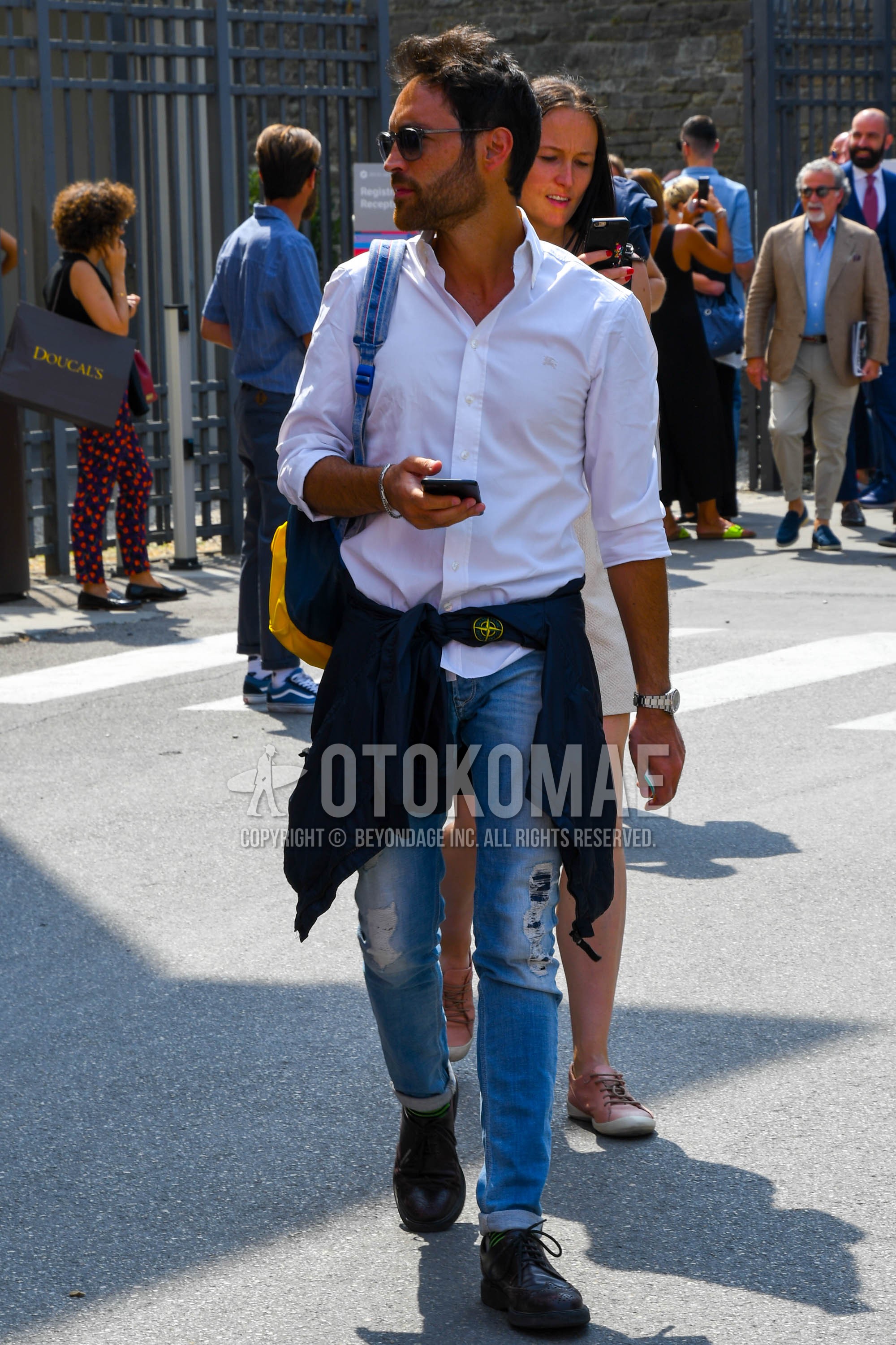 Men's spring summer outfit with clear plain sunglasses, white plain shirt, blue plain damaged jeans, green horizontal stripes socks, brown wing-tip shoes leather shoes.