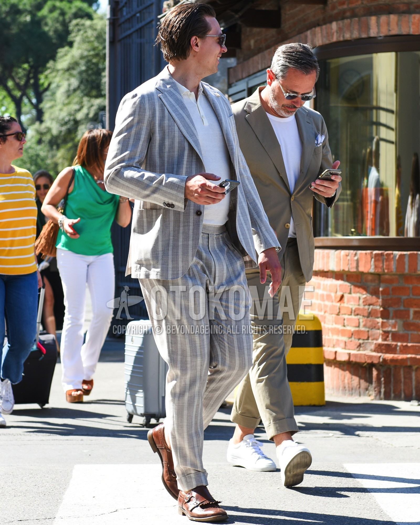 Men's spring summer outfit with silver plain sunglasses, white plain polo shirt, brown monk shoes leather shoes, green stripes suit.
