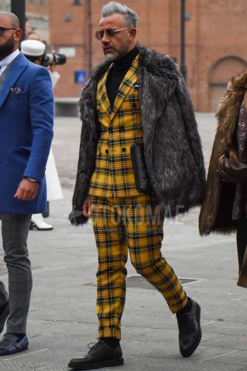 ダークグレー無地のアウター、黒無地のタートルネックニット、黒プレーントゥの革靴、イエローチェックのスーツを合わせた冬のメンズコーデ・着こなし。