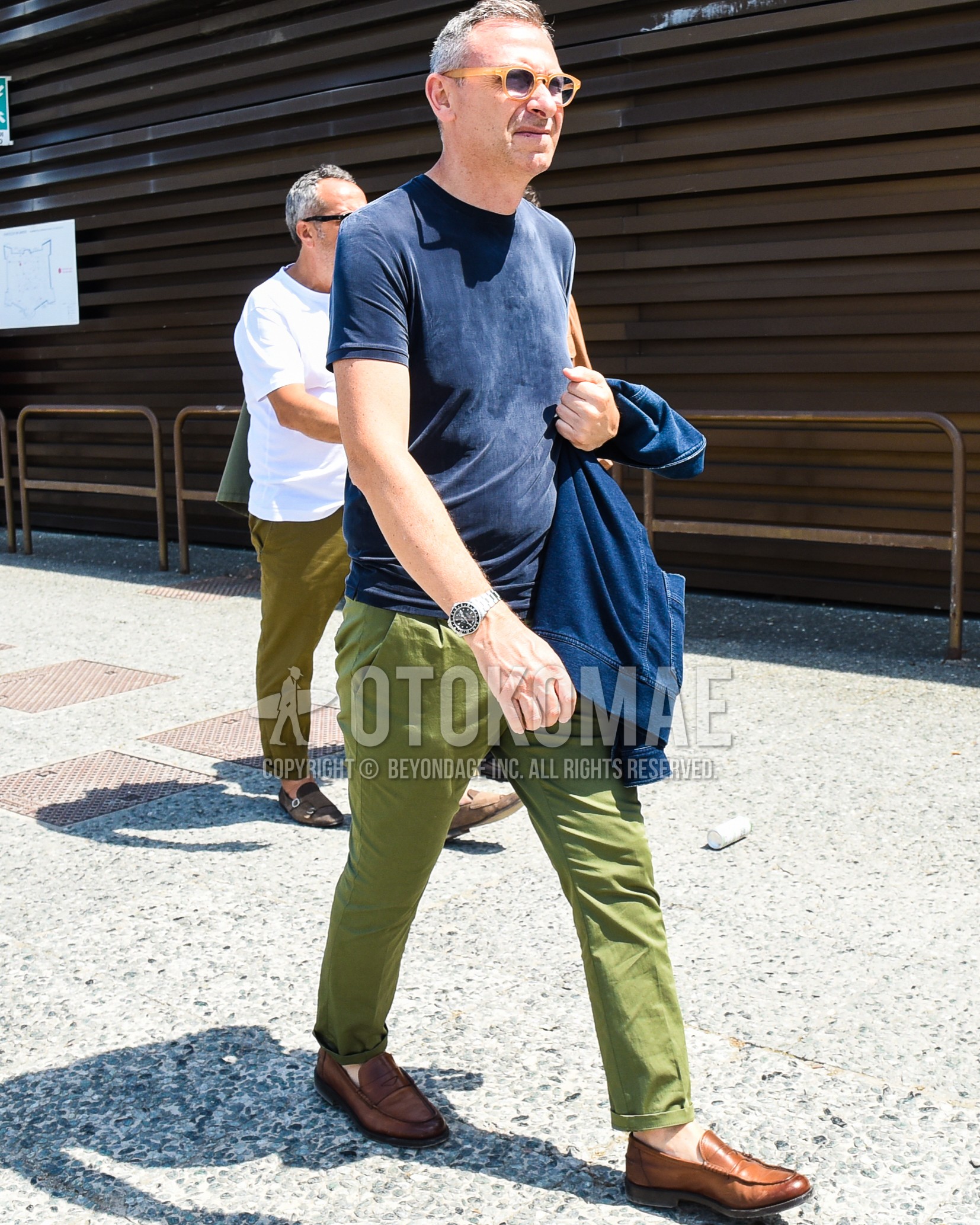 Men's spring summer outfit with black plain sunglasses, navy plain t-shirt, olive green plain cotton pants, brown coin loafers leather shoes.