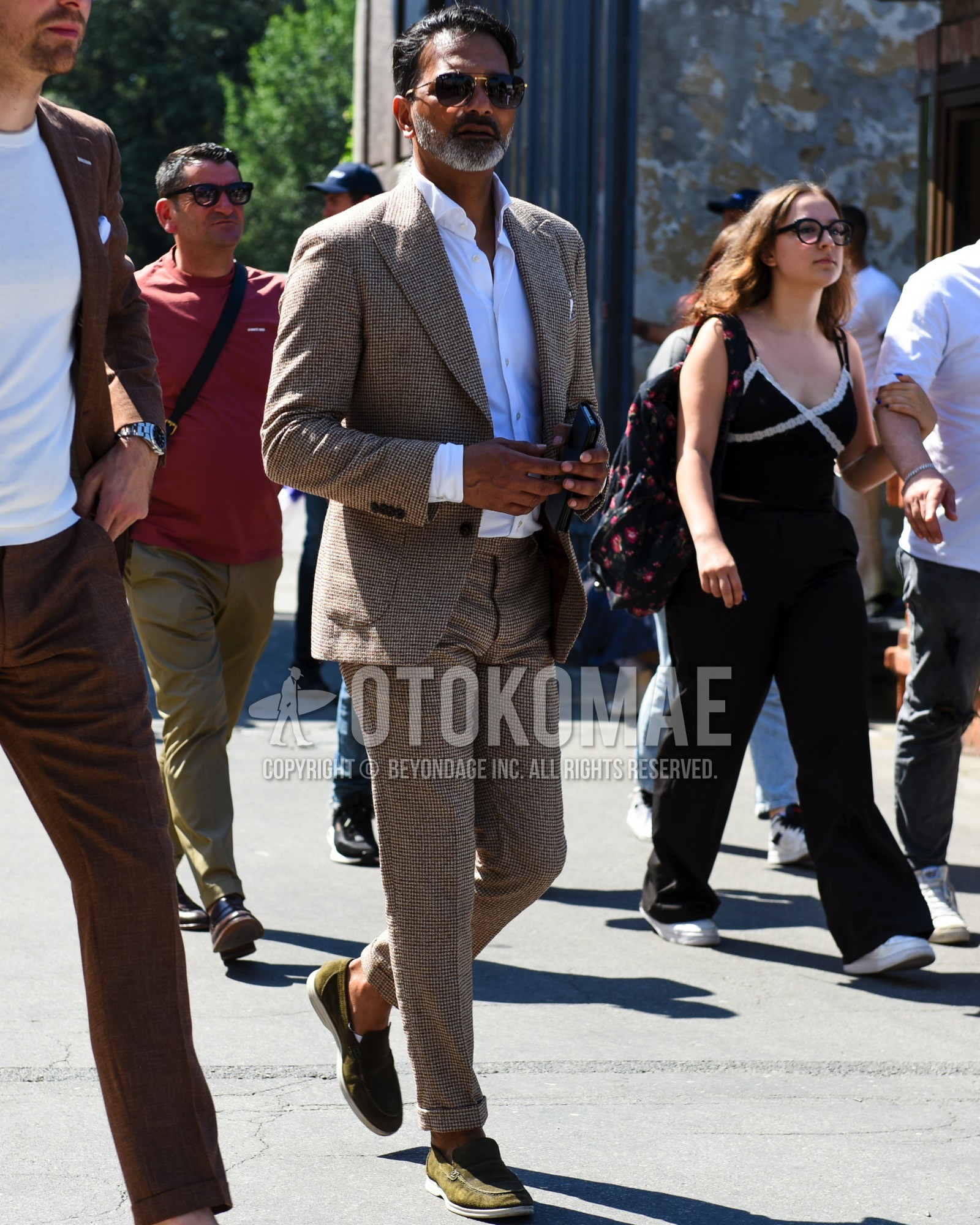 Men's spring summer outfit with brown plain sunglasses, white plain shirt, olive green slip-on sneakers, brown check suit.