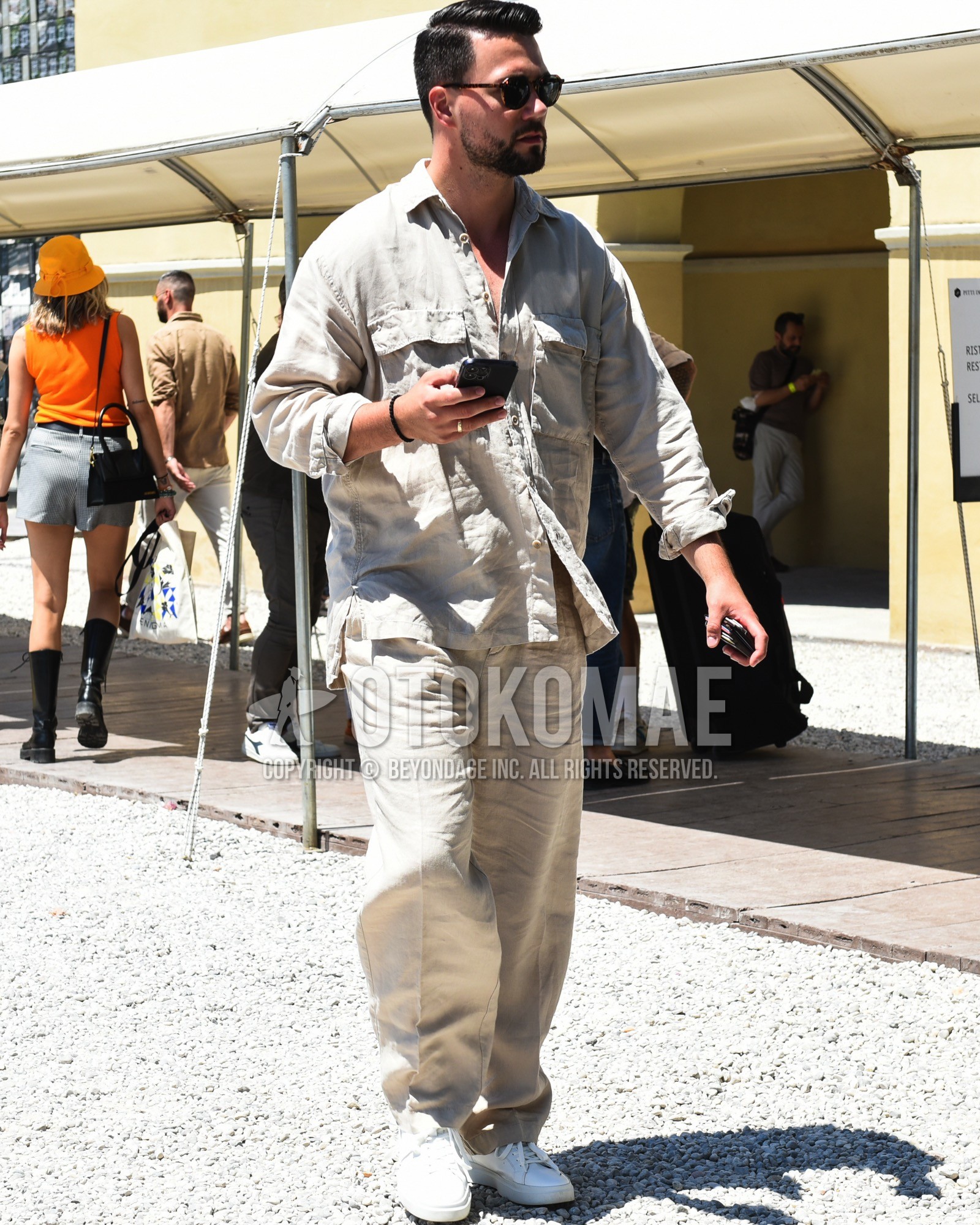 Men's spring summer outfit with brown tortoiseshell sunglasses, white low-cut sneakers, beige plain casual setup.