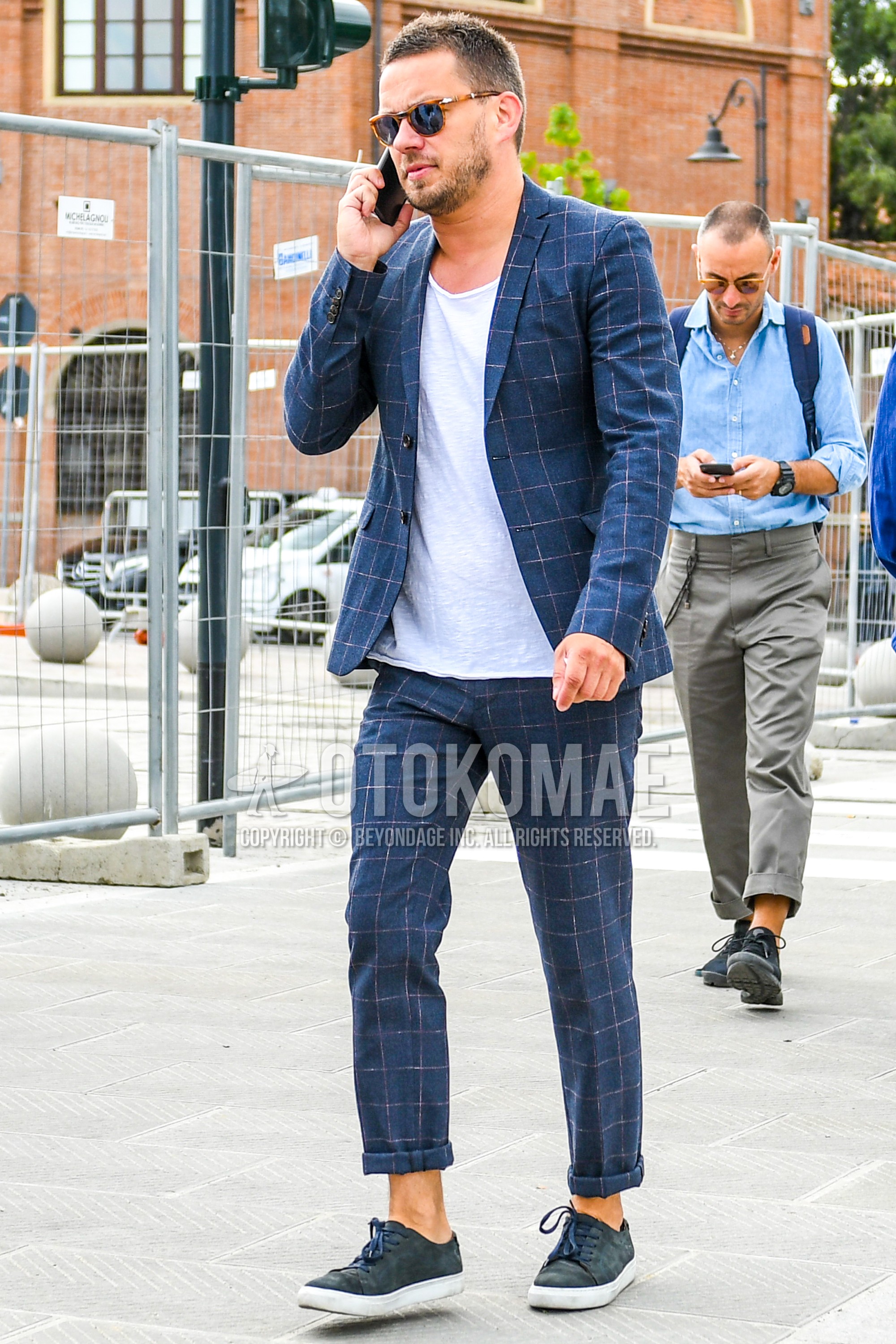 Men's spring summer autumn outfit with tortoiseshell sunglasses, white plain t-shirt, navy low-cut sneakers, navy check suit.