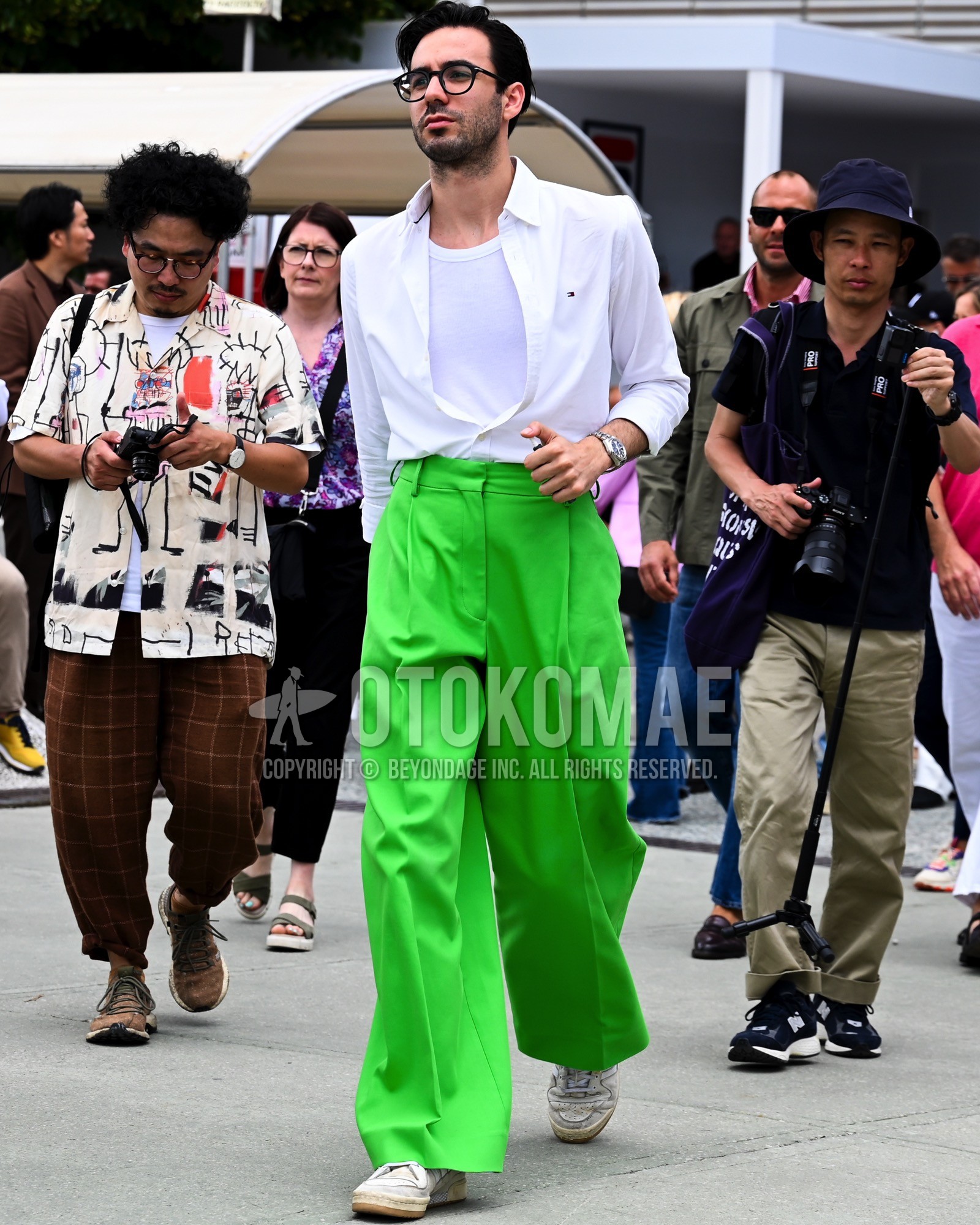 Men's spring summer autumn outfit with clear plain sunglasses, white plain tailored jacket, white plain t-shirt, green plain wide pants, white low-cut sneakers.