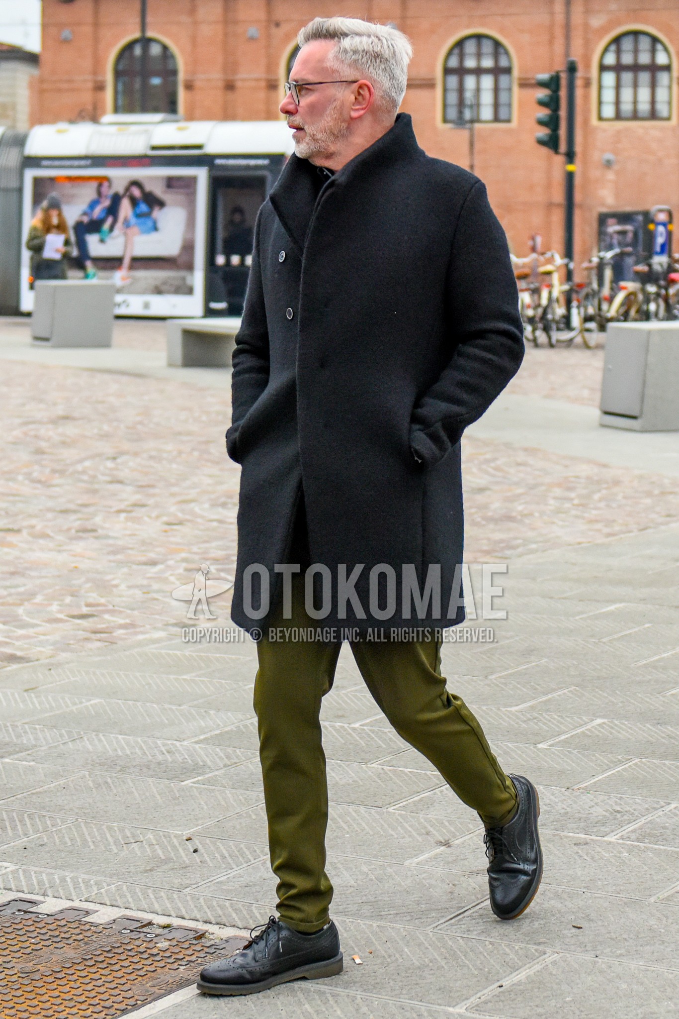 Men's winter outfit with black plain glasses, black plain stand collar coat, olive green plain cotton pants, black brogue shoes leather shoes.