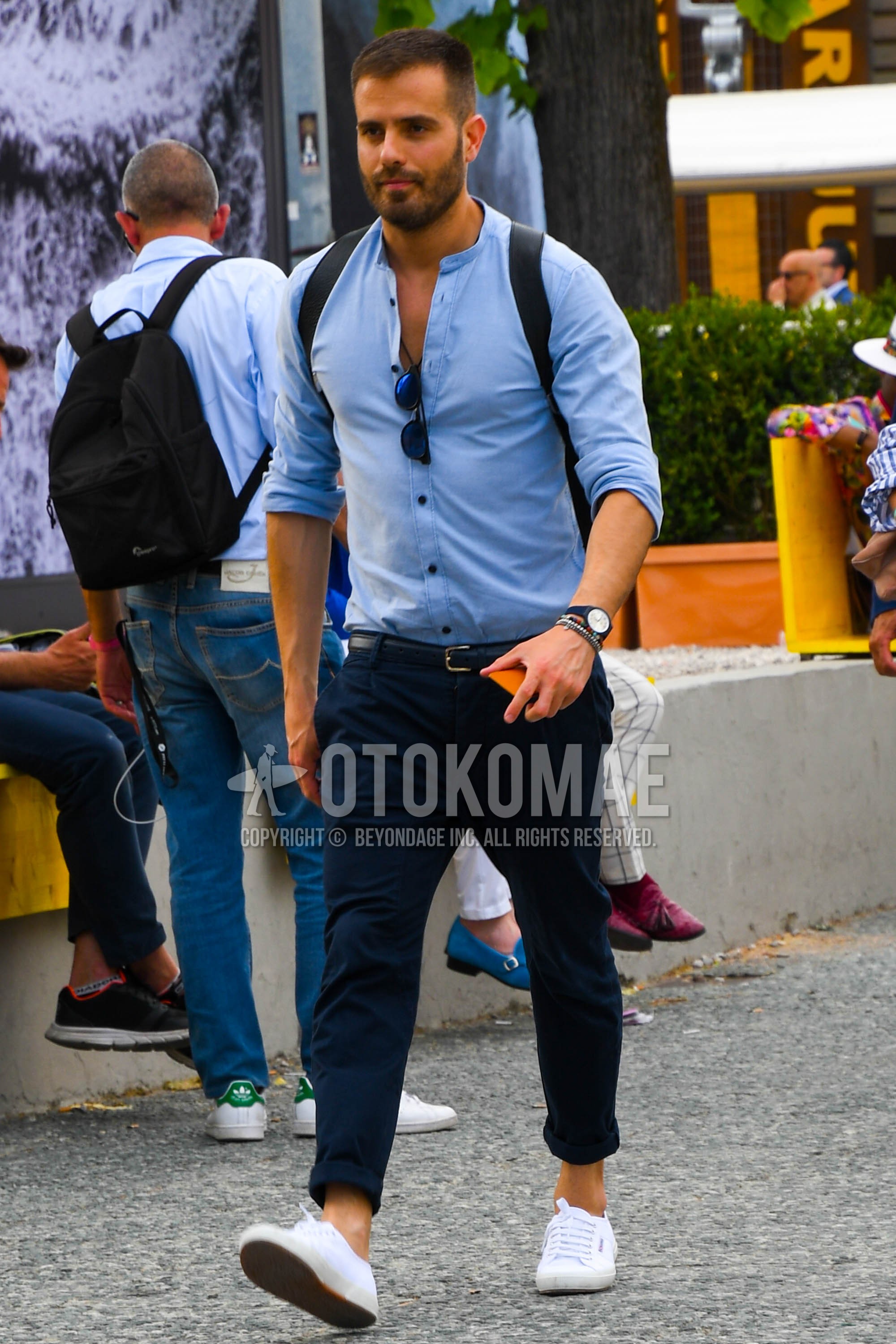 Men's spring summer outfit with light blue plain shirt, black plain leather belt, navy plain chinos, white low-cut sneakers.