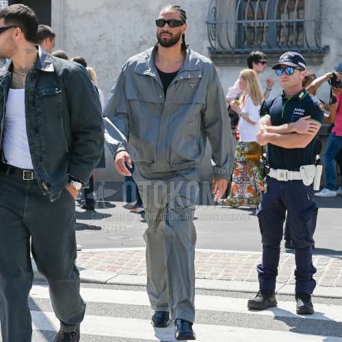 黒無地のサングラス、プラダのグレー無地のアウター、黒無地のTシャツ、プラダのグレー無地のボトムス、黒コインローファーの革靴を合わせた夏春のメンズコーデ・着こなし。