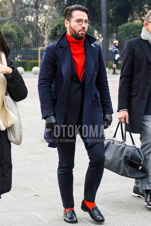Men's autumn winter outfit with brown tortoiseshell glasses, navy plain ulster coat, red plain turtleneck knit, red plain socks, black coin loafers leather shoes, dark gray stripes suit.