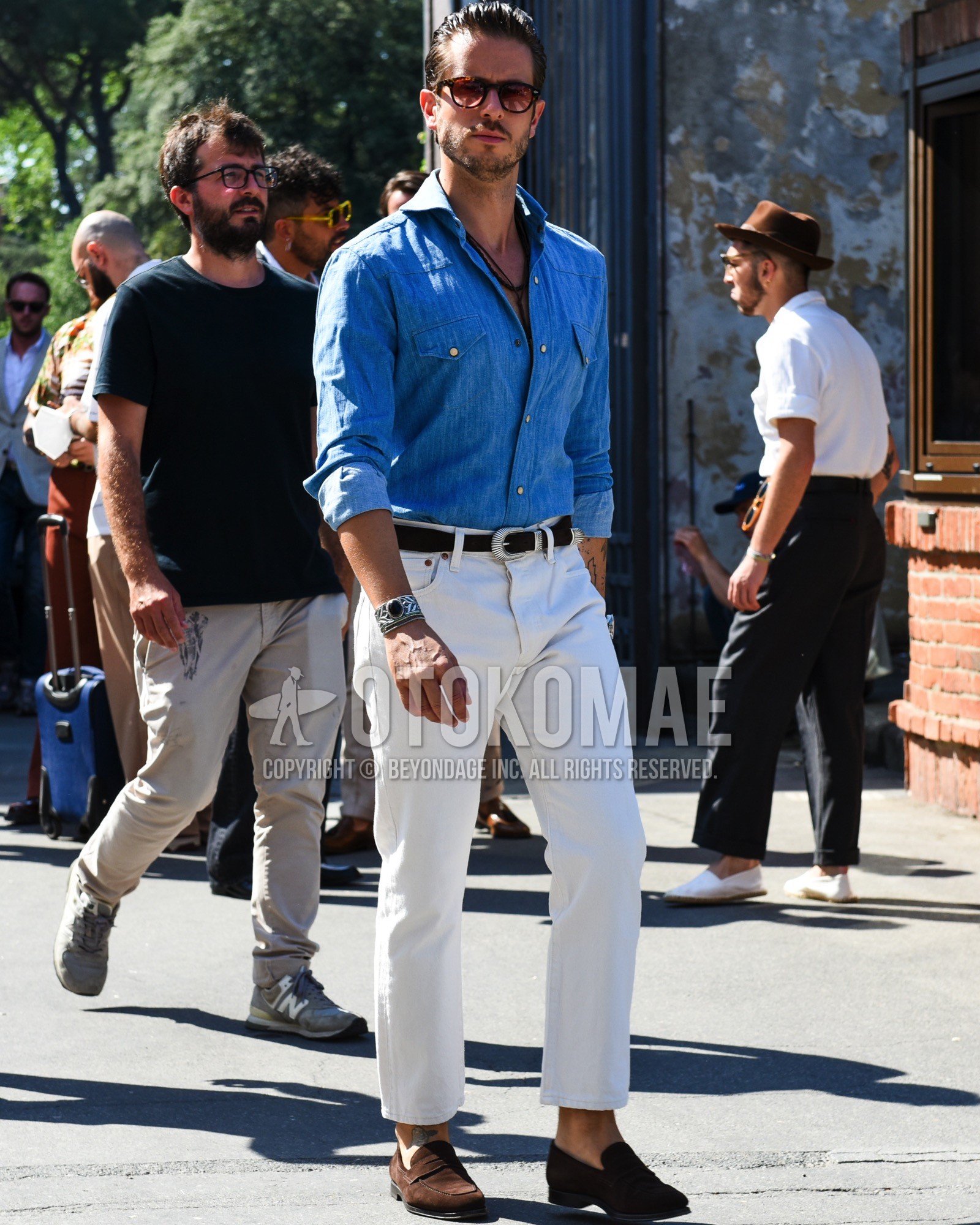 Men's spring summer outfit with brown tortoiseshell sunglasses, blue plain denim shirt/chambray shirt, black plain leather belt, white plain cotton pants, white plain ankle pants, brown coin loafers leather shoes.