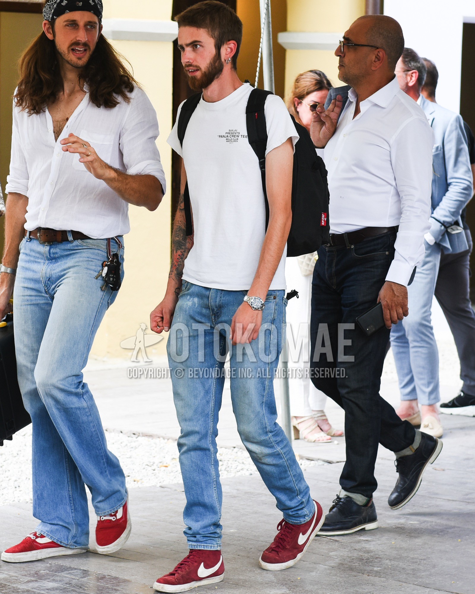 Men's spring summer outfit with white one point t-shirt, blue plain denim/jeans, red high-cut sneakers, black plain backpack.