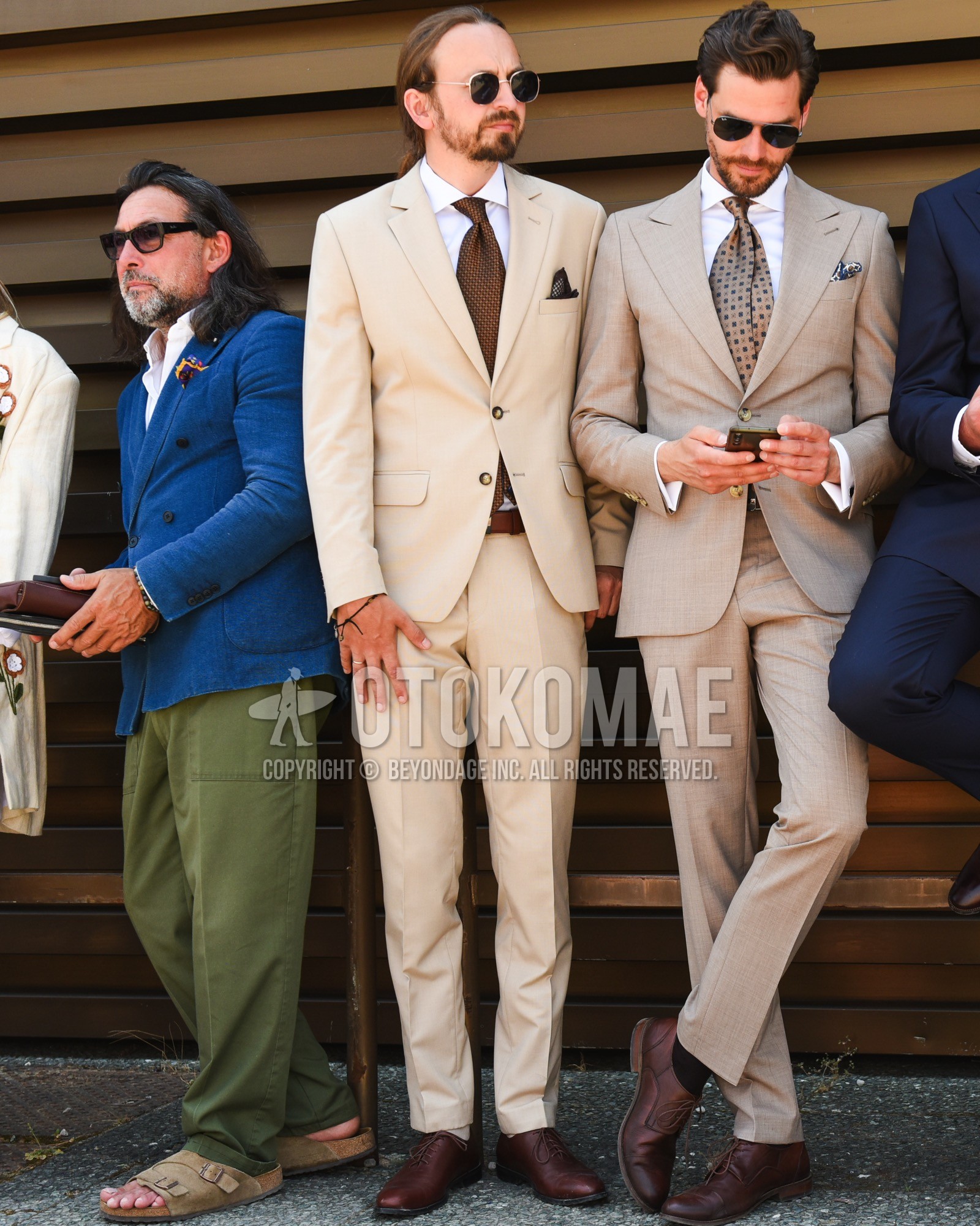 Men's spring summer outfit with gold plain sunglasses, white plain shirt, brown plain leather belt, beige plain suit, brown small crest necktie.