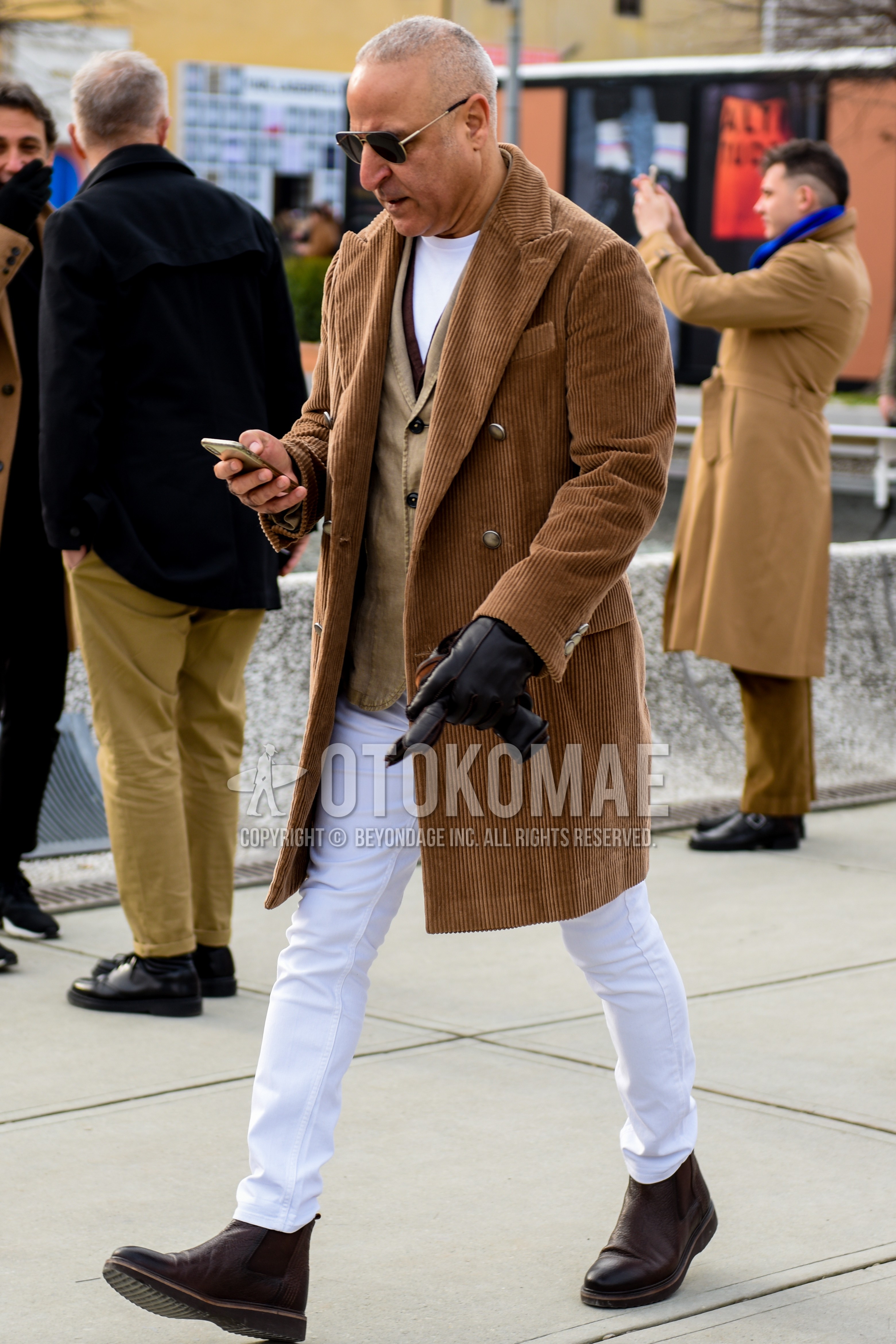 Men's autumn winter outfit with brown plain chester coat, beige plain tailored jacket, white plain t-shirt, white plain cotton pants, brown side-gore boots.