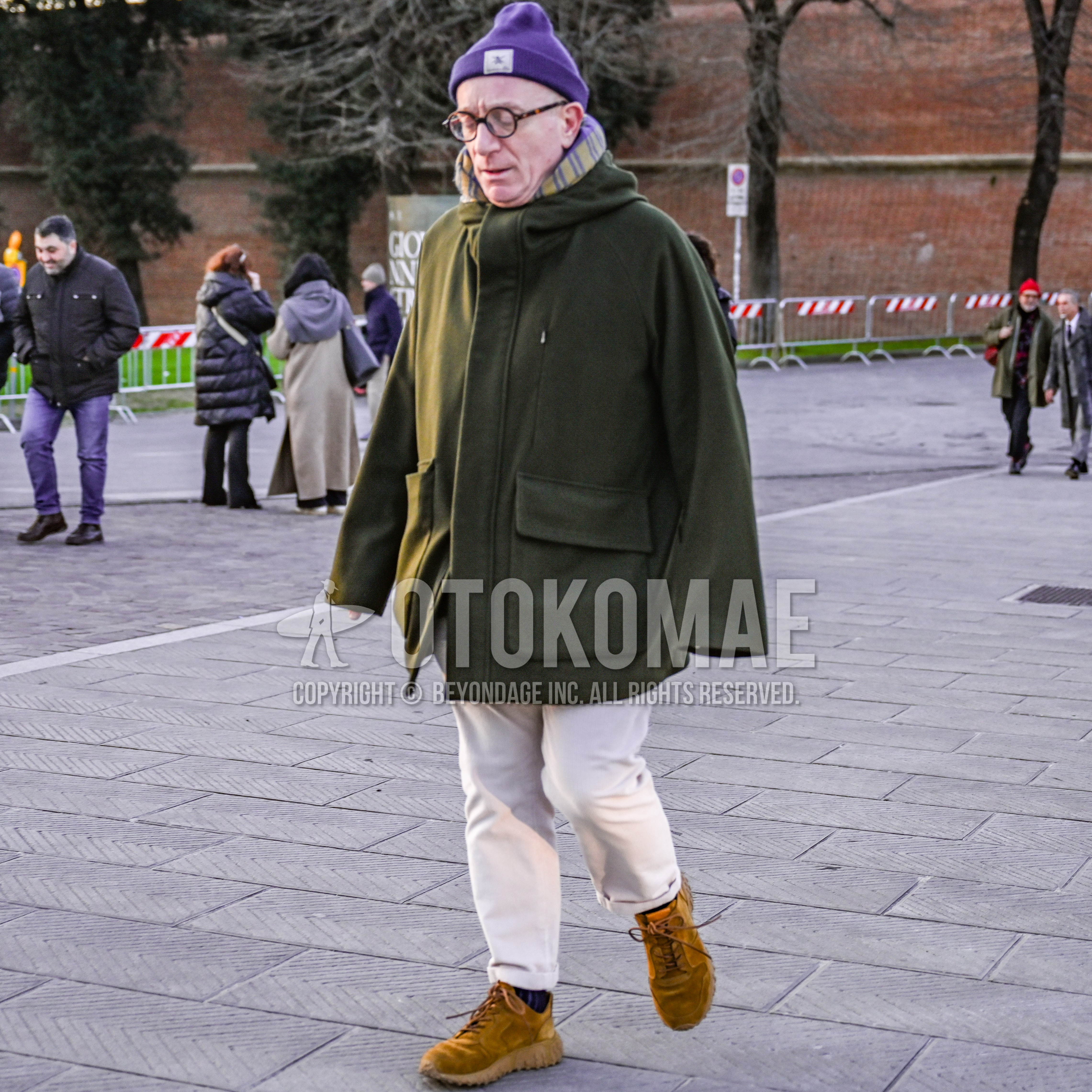 Men's autumn winter outfit with purple one point knit cap, brown tortoiseshell glasses, purple yellow stripes scarf, olive green plain hooded coat, white plain cotton pants, navy stripes socks, brown sneakers.