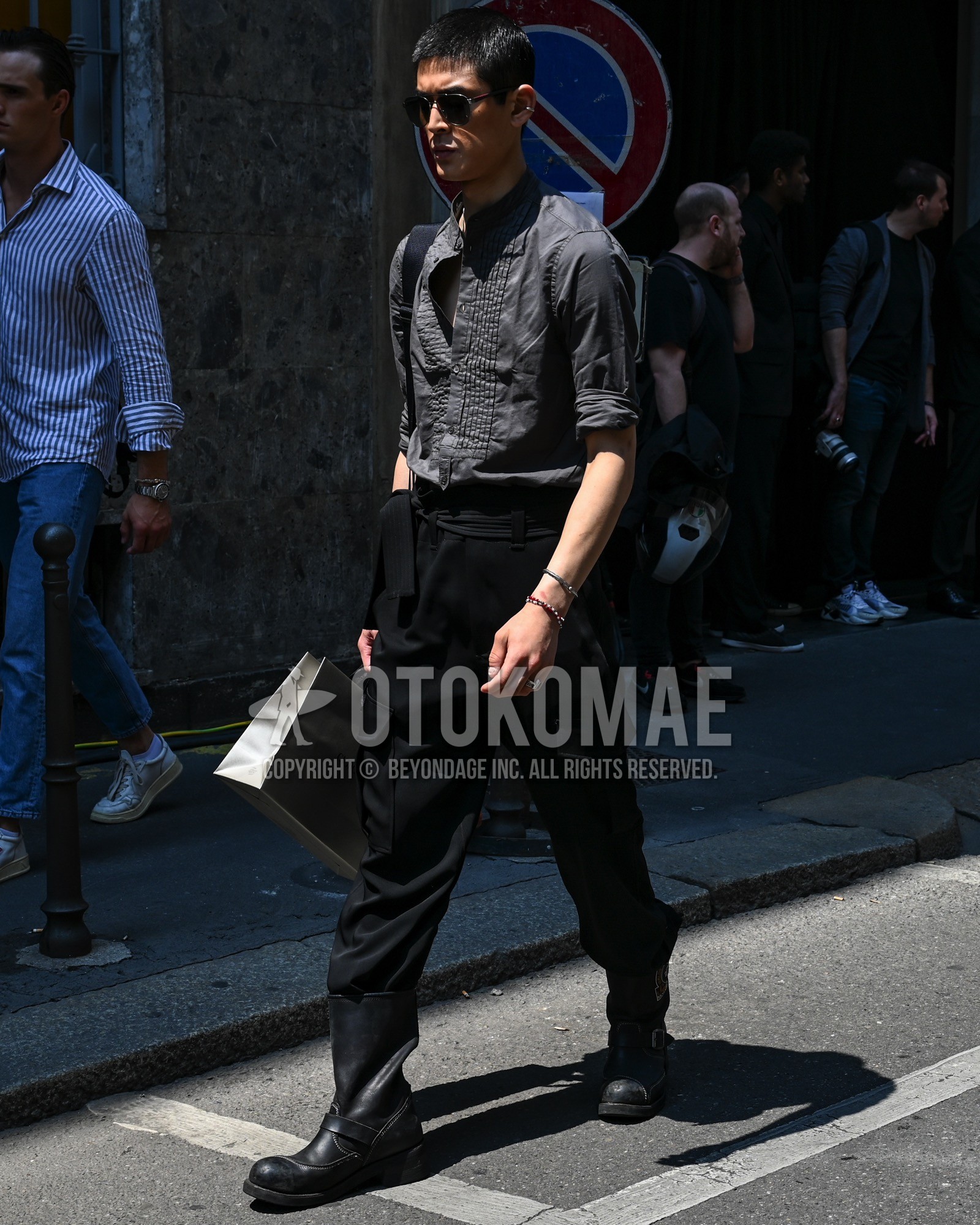 Men's spring summer autumn outfit with black plain shirt, black plain beltless pants, black  boots, black plain shoulder bag.