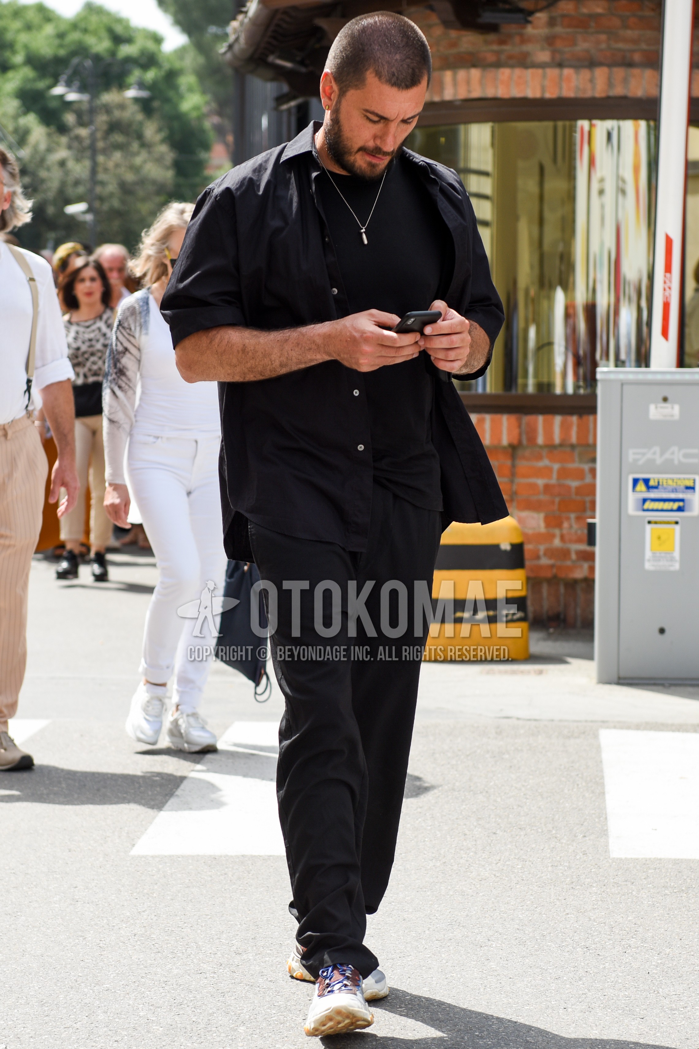 Men's spring summer outfit with black plain shirt, black plain t-shirt, black plain cotton pants, white low-cut sneakers.