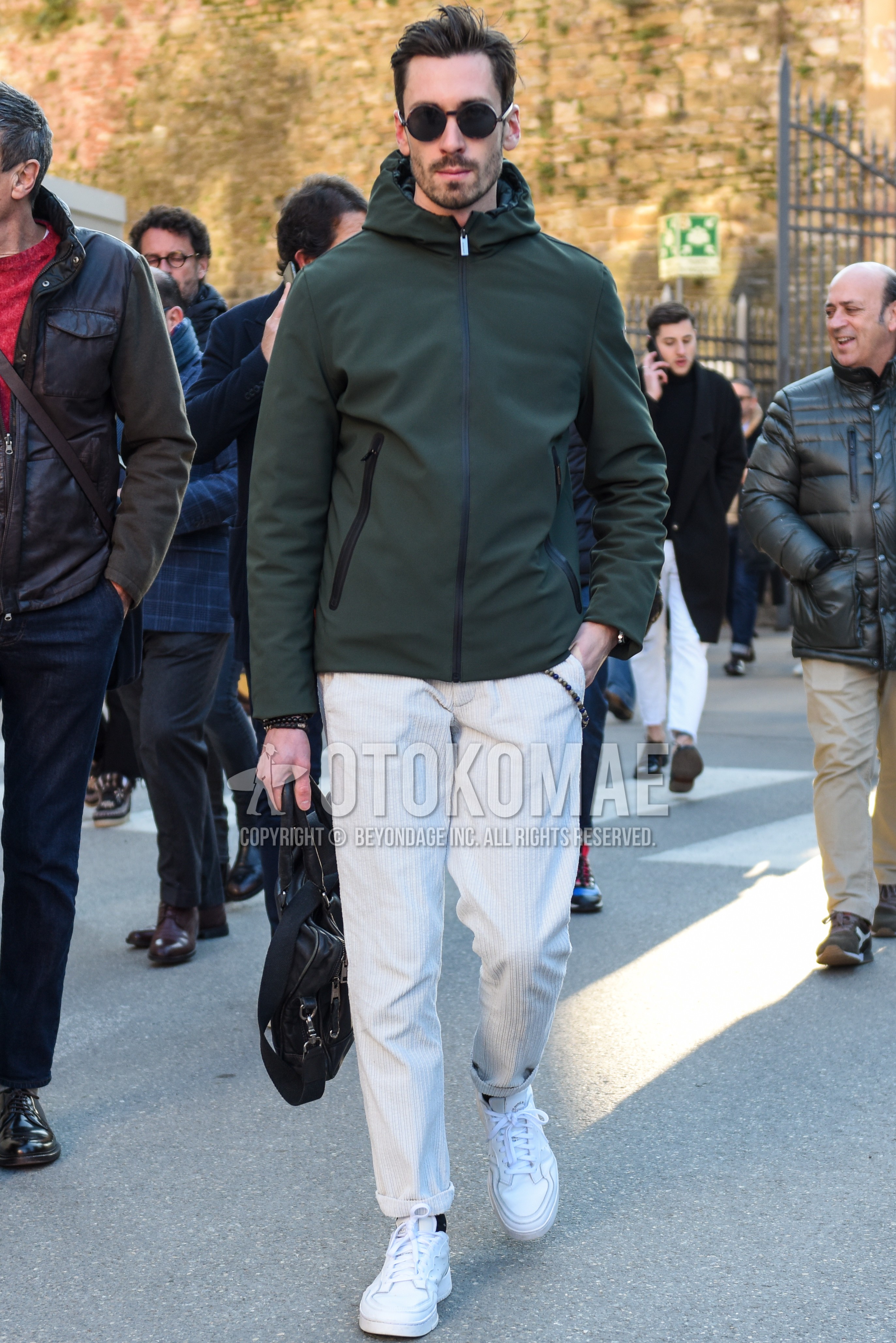 Men's autumn winter outfit with black plain sunglasses, green plain mountain parka, white plain winter pants (corduroy,velour), black plain socks, white low-cut sneakers.
