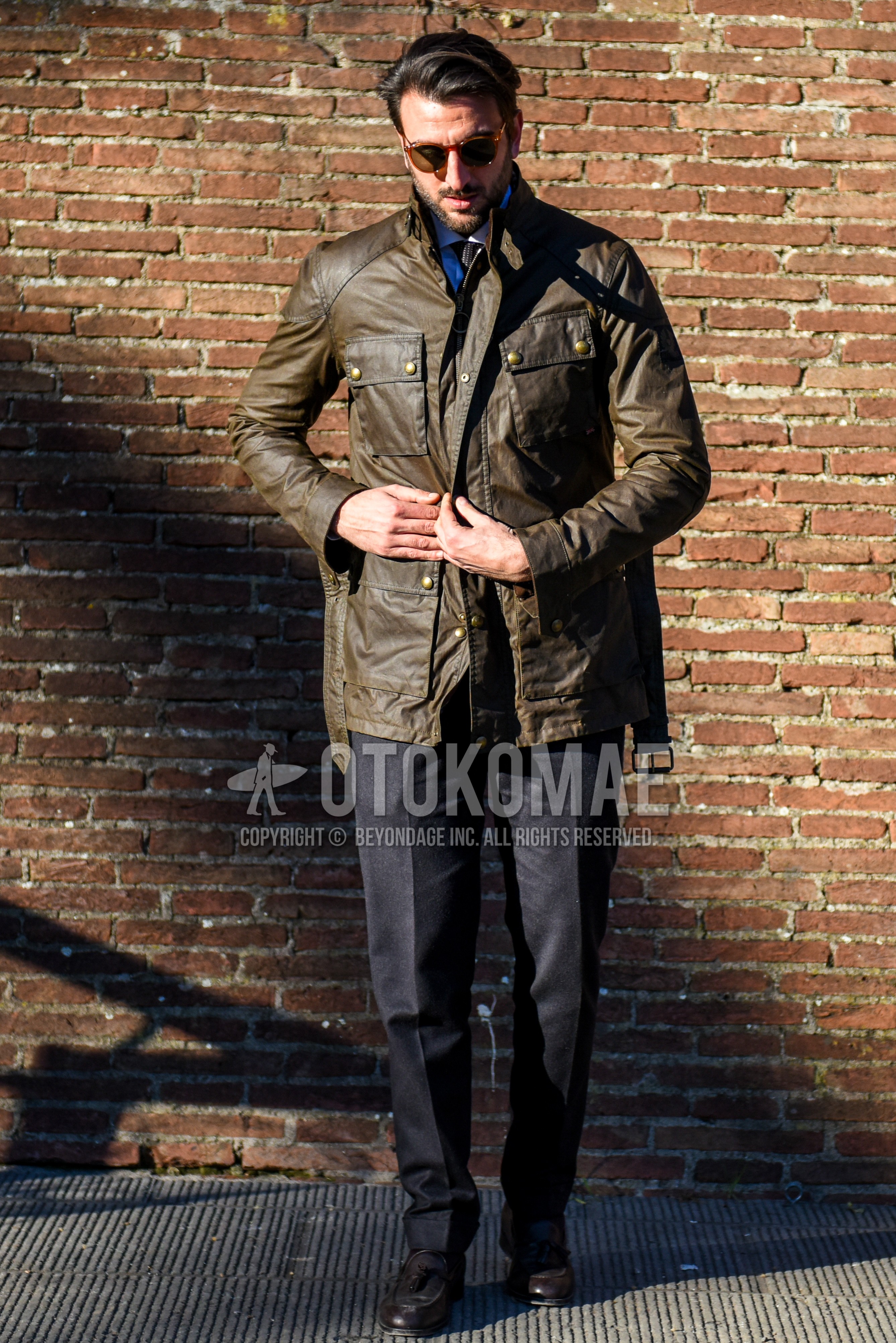 Men's winter outfit with plain sunglasses, brown plain field jacket/hunting jacket, black plain slacks, brown tassel loafers leather shoes.